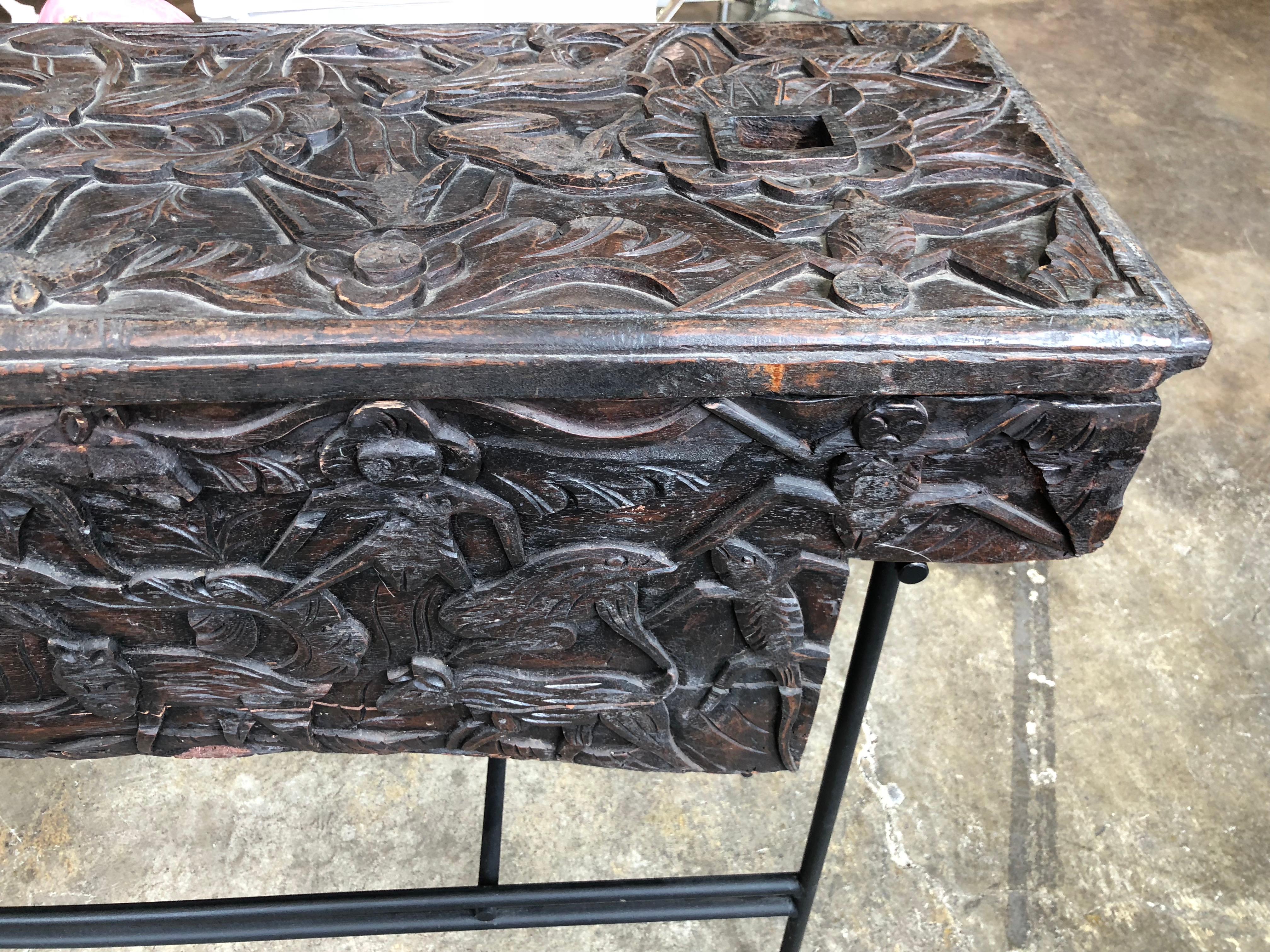 Carved African wood wedding chest on metal custom stand now functioning as a console table or sideboard having a removable top and an overall intricately carved figural animal, fish and human design.