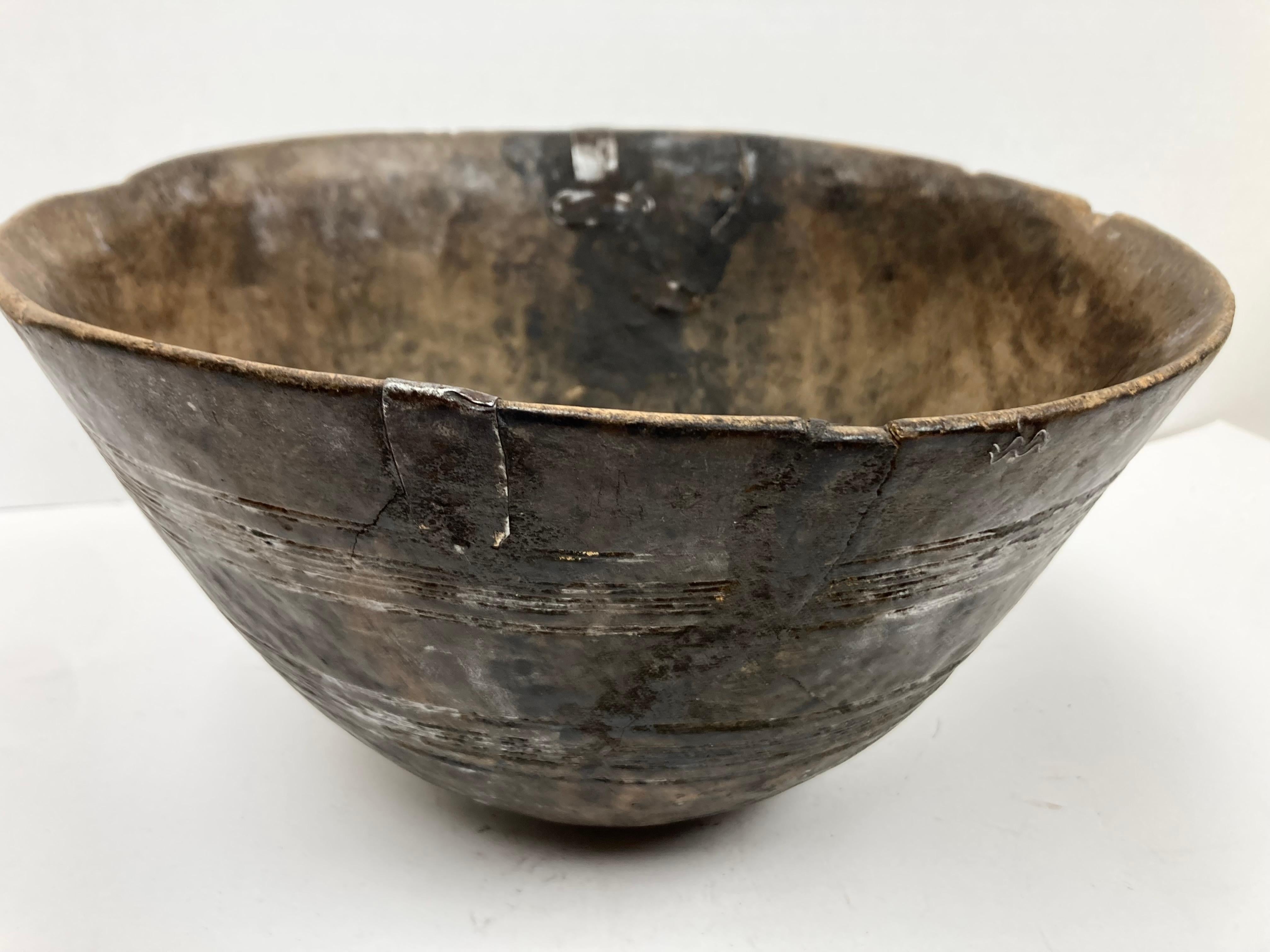 Un'autentica ciotola in Wood Wood africano, usurata e con decorazioni incise. La ciotola, di buone dimensioni, equilibrata e con una patina marrone intenso, presenta una decorazione incisa in due bande all'esterno. Molto usurata da lunghi anni di