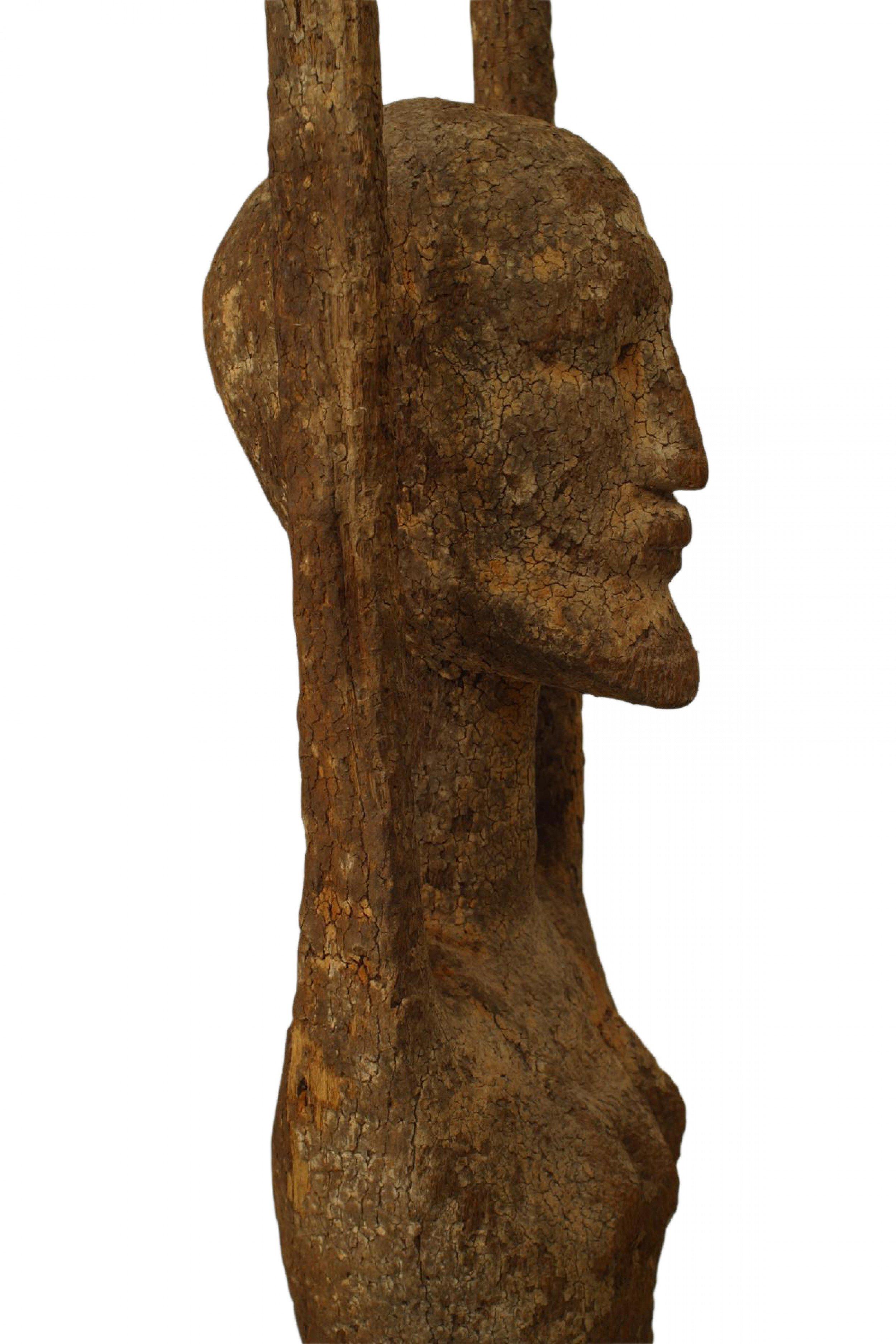 Figure nue en bois sculpté africain d'un dieu de la fertilité (Dongo Mago) avec les mains levées et debout sur une base ébénisée (19e siècle).
    