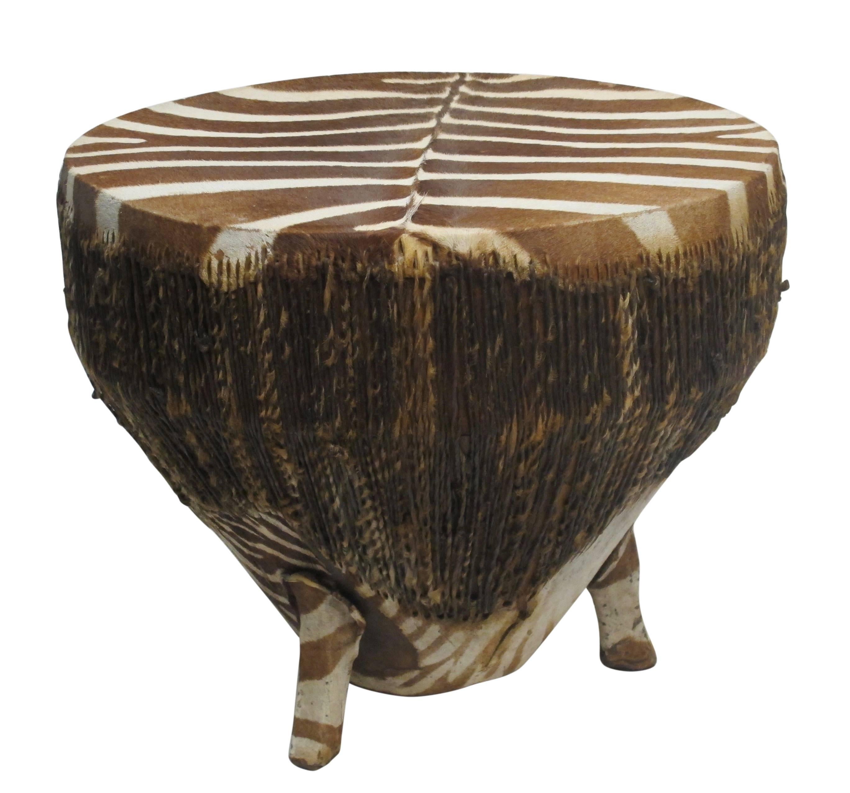 Zebra hide stretched over wooden drum with twisted rawhide around the sides standing on three zebra covered legs, African, early 20th century.
