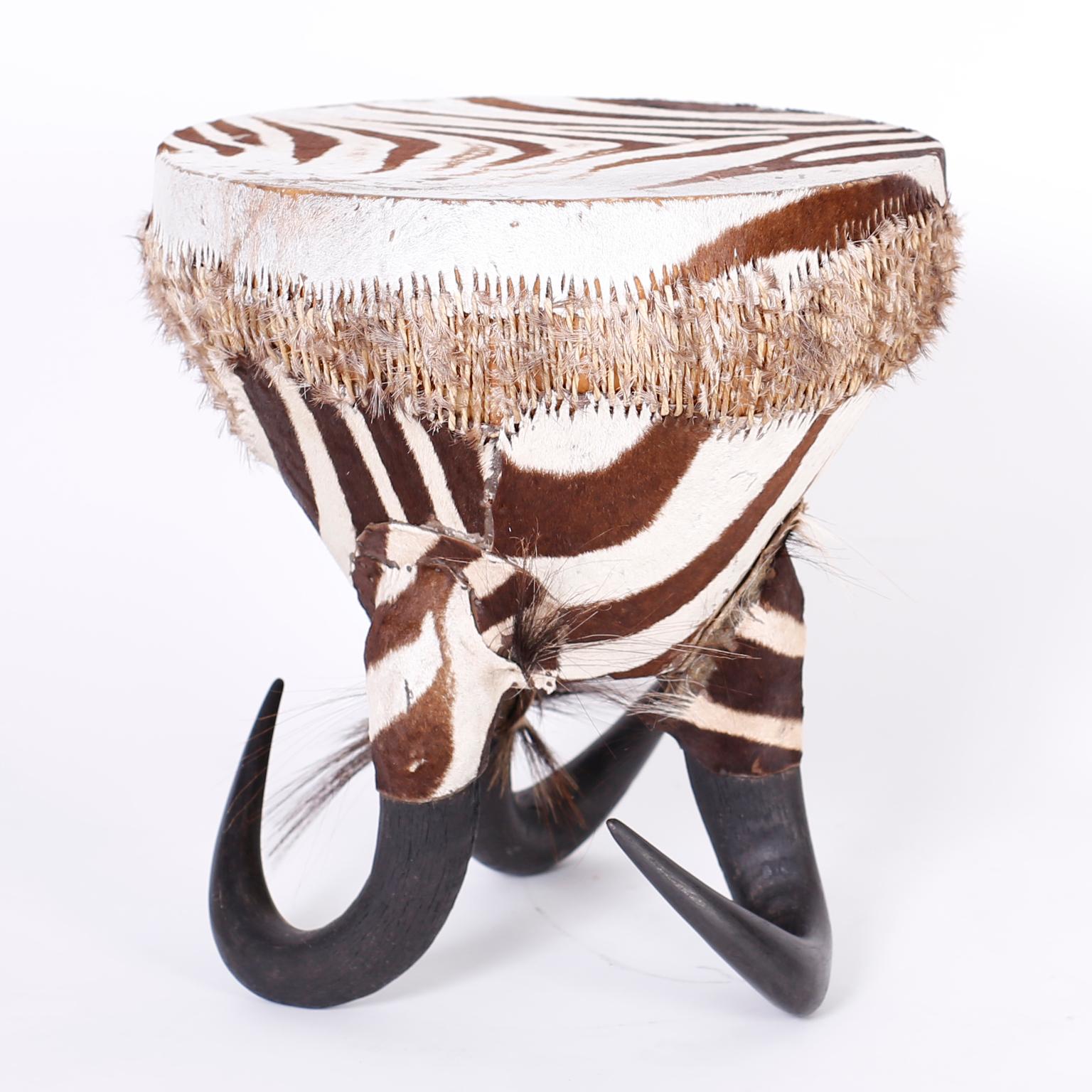 Unusual mid century drum table covered in zebra hide and supported by three horn feet.