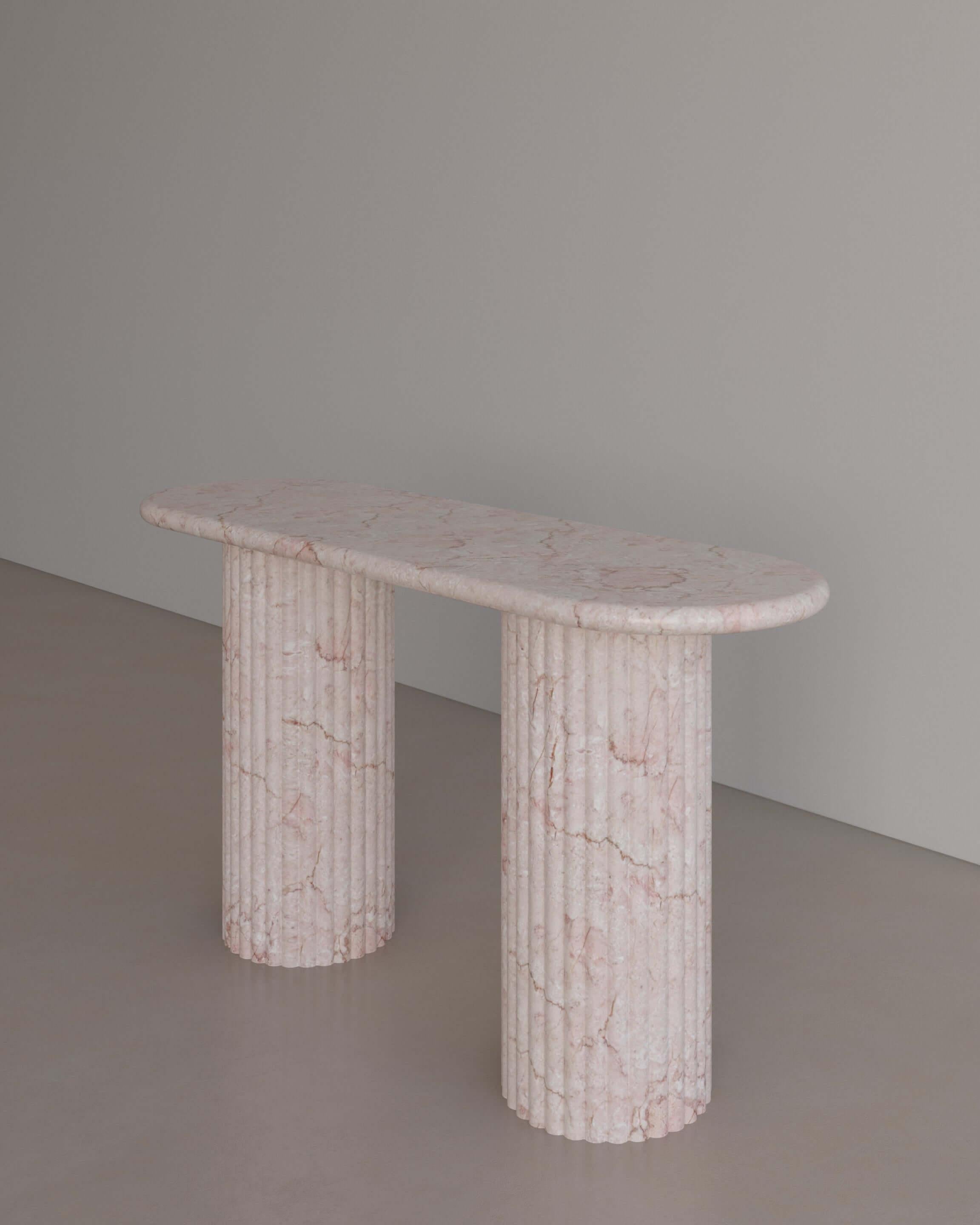 The Essentialist presents The Antica Console table in Afshar Pink Marble. Featuring two Roman-style pillars, used throughout the Empire’s history to celebrate conquest and victory. Featuring a sensuous, elongated oval top with bullnose edges resting