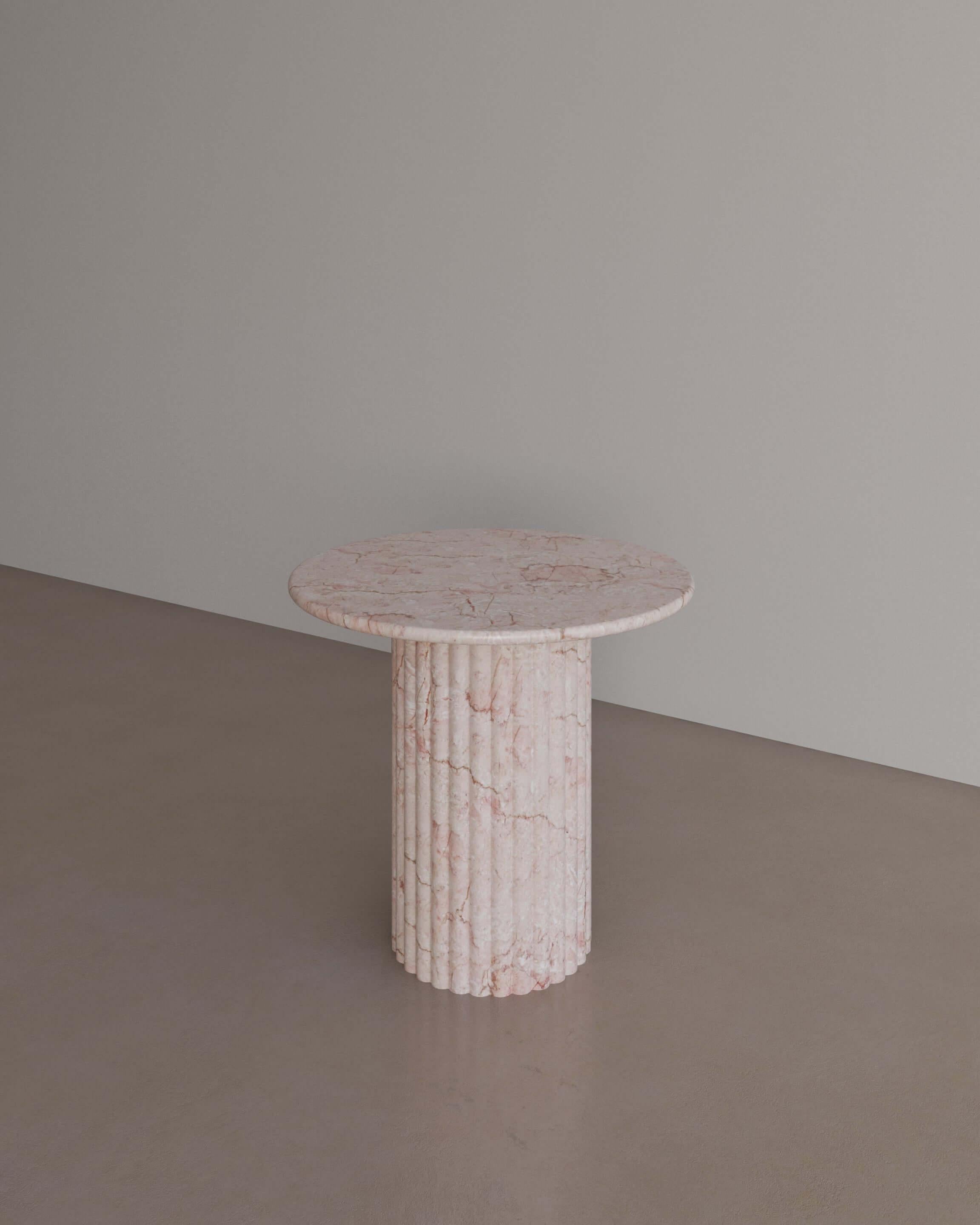The Antica Occasional table in Afshar Pink Marble by The Essentialist displays a perfect synergy by viewing classical idealism through a modern lens. A traditional pillar supports a circular top with bullnose edges, crafted from whole natural