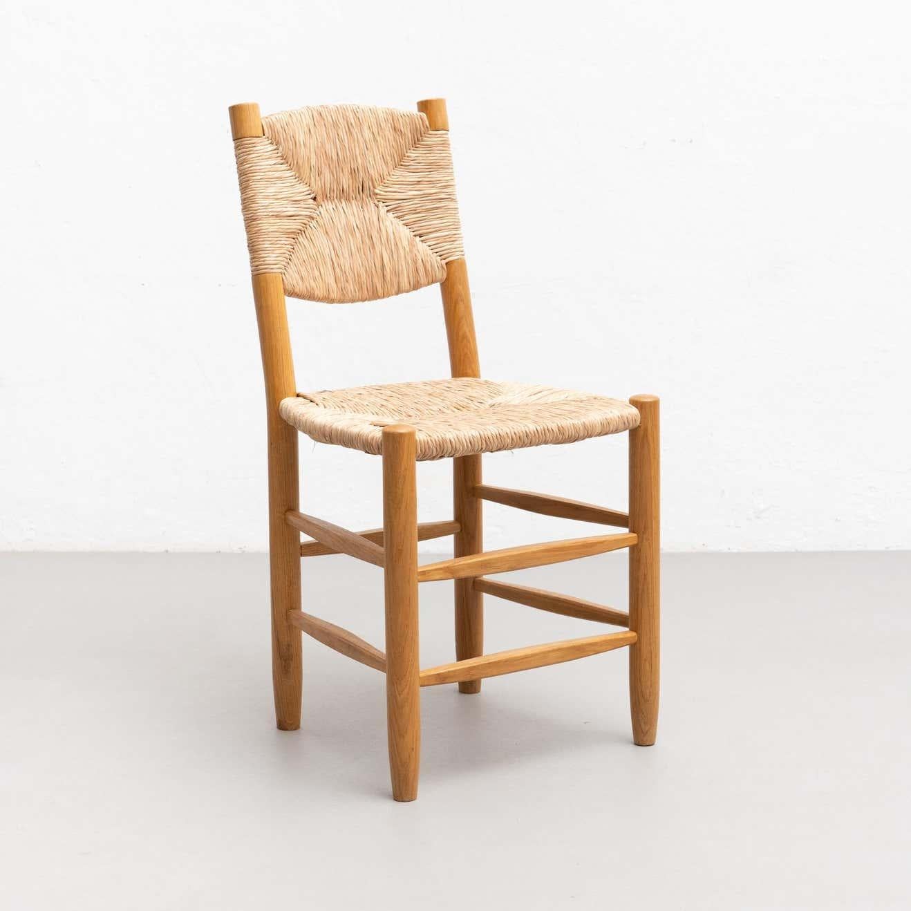 Chair designed in the style of Charlotte Perriand, made by unknown manufacturer, circa 1980.

Wood and rattan.

In good original condition, with minor wear consistent with age and use, preserving a beautiful patina.