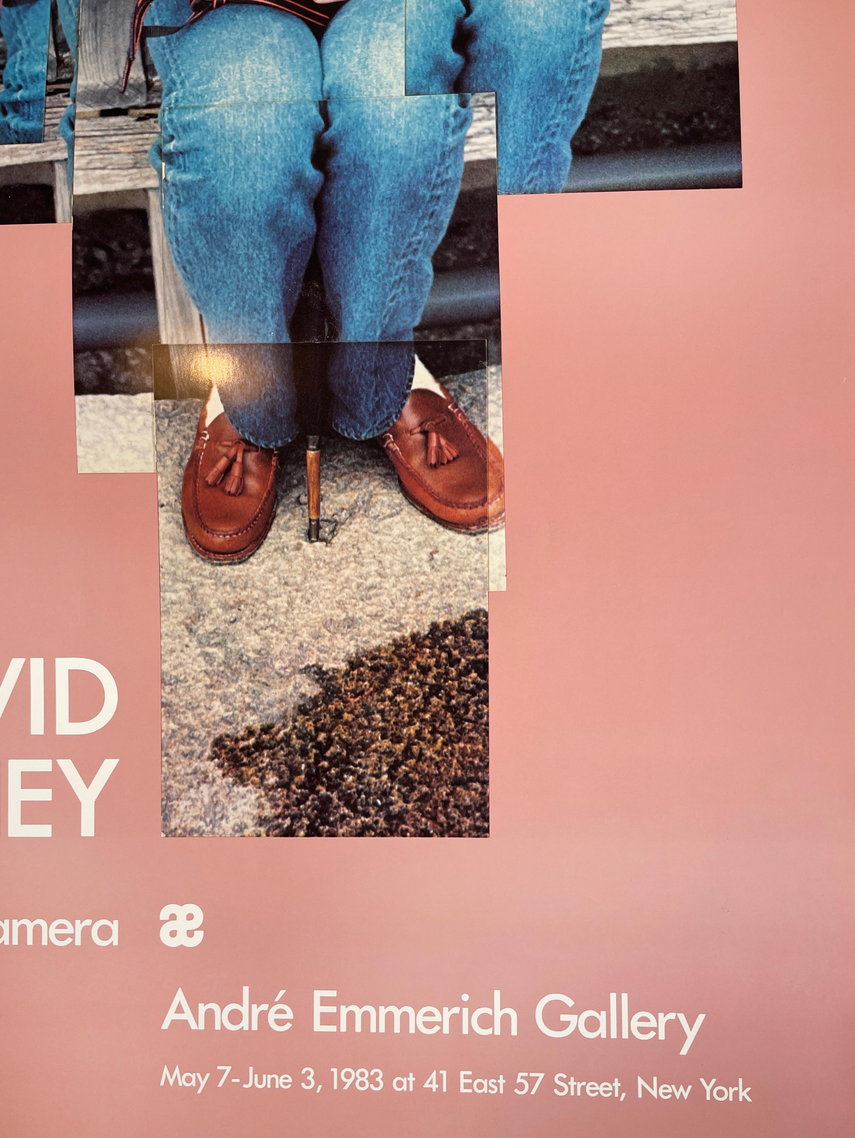 Questo poster vintage di una mostra presenta un collage fotografico di David Hockney.  Un giovane uomo con una zazzera di riccioli che indossa mocassini di pelle marrone si accovaccia sulla sua macchina fotografica, ricaricando la pellicola. Si