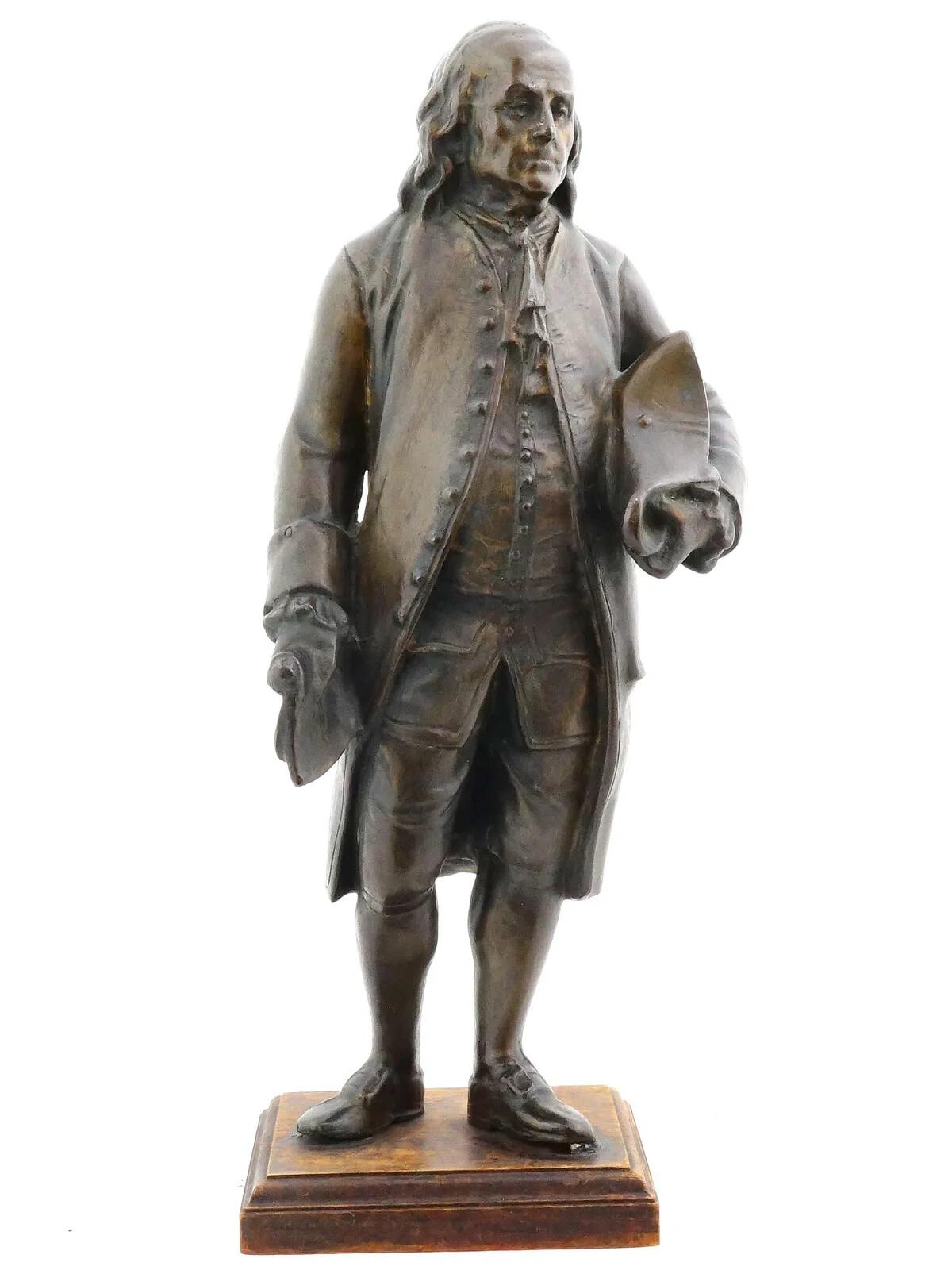 After Francois Marie Suzanne, French, 1750 to 1813, a bronze standing figure of Benjamin Franklin holding a tricorn and a scroll. On a wooden base. Circa the 1850s. Francois Marie Suzanne was a sculptor. His works included a full-length statuette of