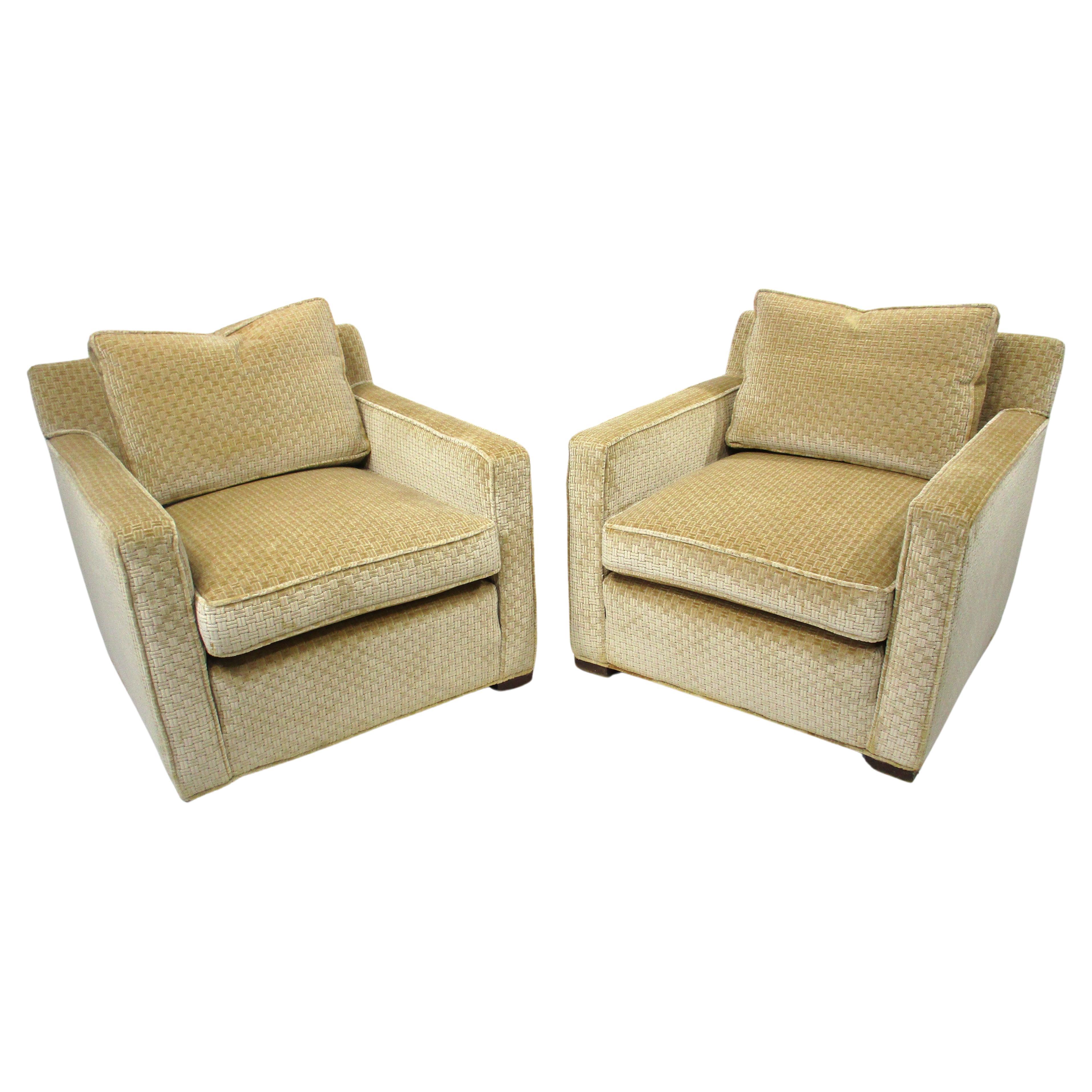 A pair of wonderfully comfortable and supportive club chairs in a soft medium beige colored cross hatched patterned fabric . Very well crafted and sturdy with loose cushions and springs to the bottom of the chairs in the manner of Dunbar . Designed