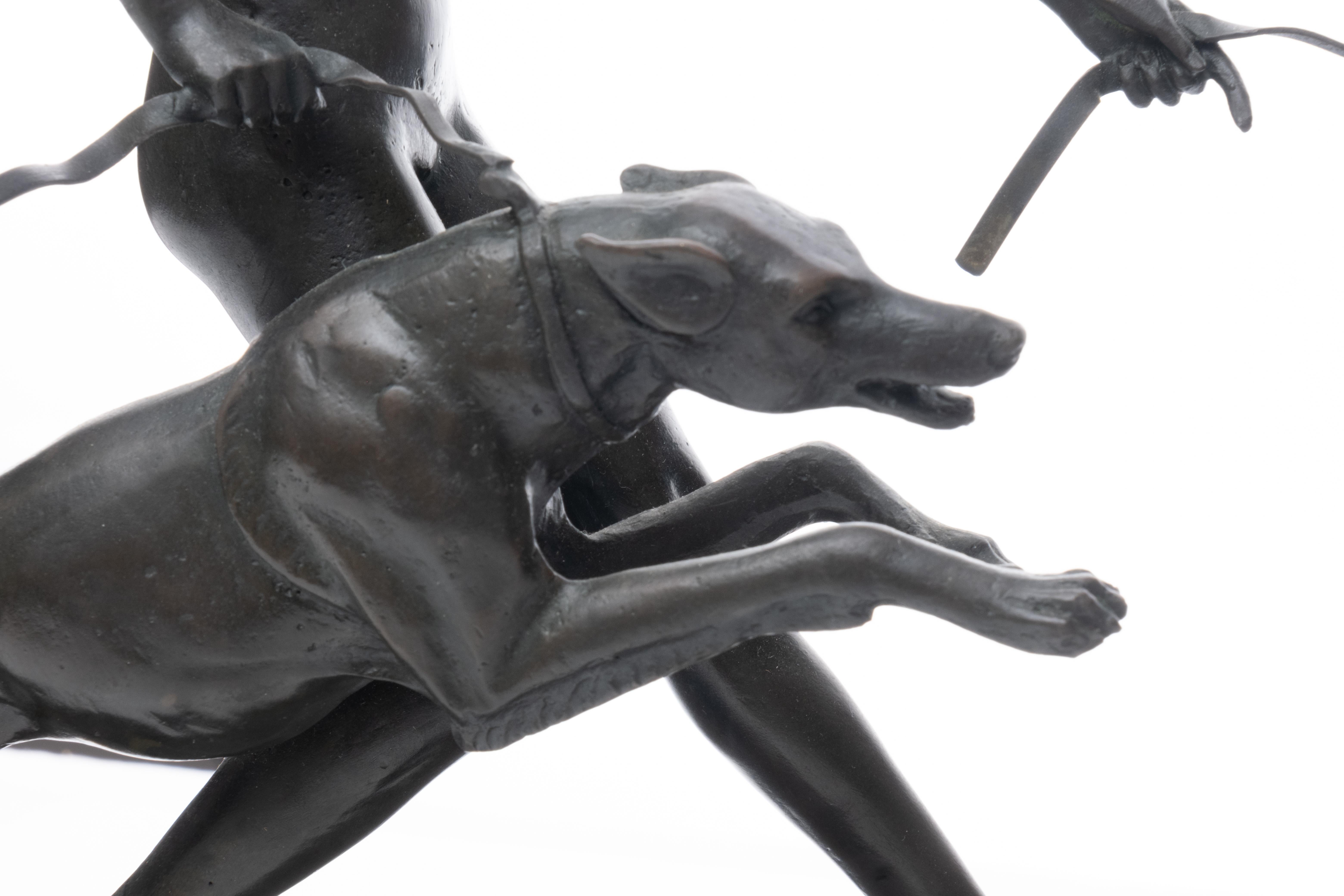 D'après Marcel Bouraine (français, 1886-1948) Sculpture en bronze Art déco représentant une femme nue courant avec des chiens. Sur une base rectangulaire en marbre noir plintée. Signé 