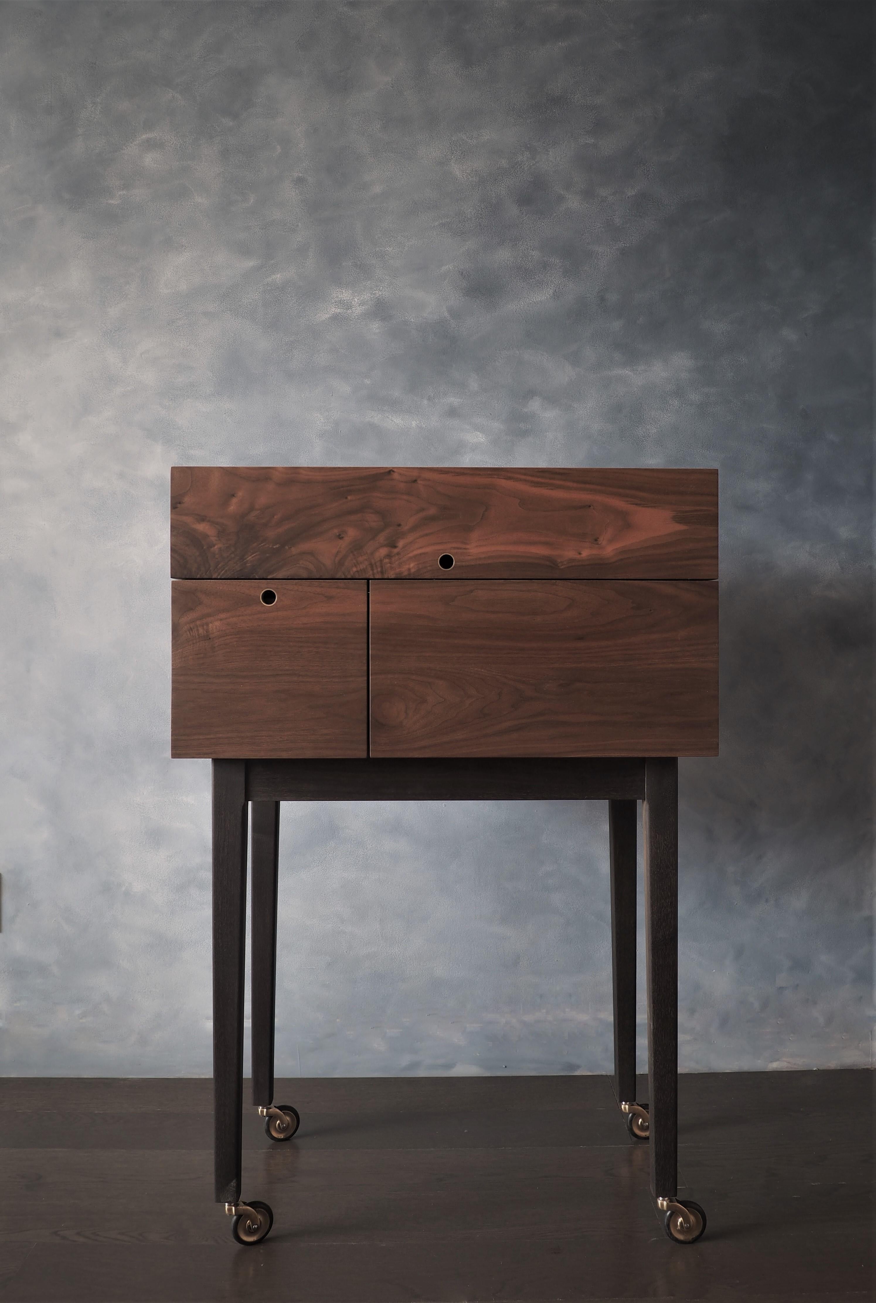 Our after midnight liquor cart is constructed out of solid walnut and featuring brass wheels, brass hardware, and brass pulls. Midnight blue leather top and a soft close drawer for your favourite glassware. It has oxidized solid walnut legs and the