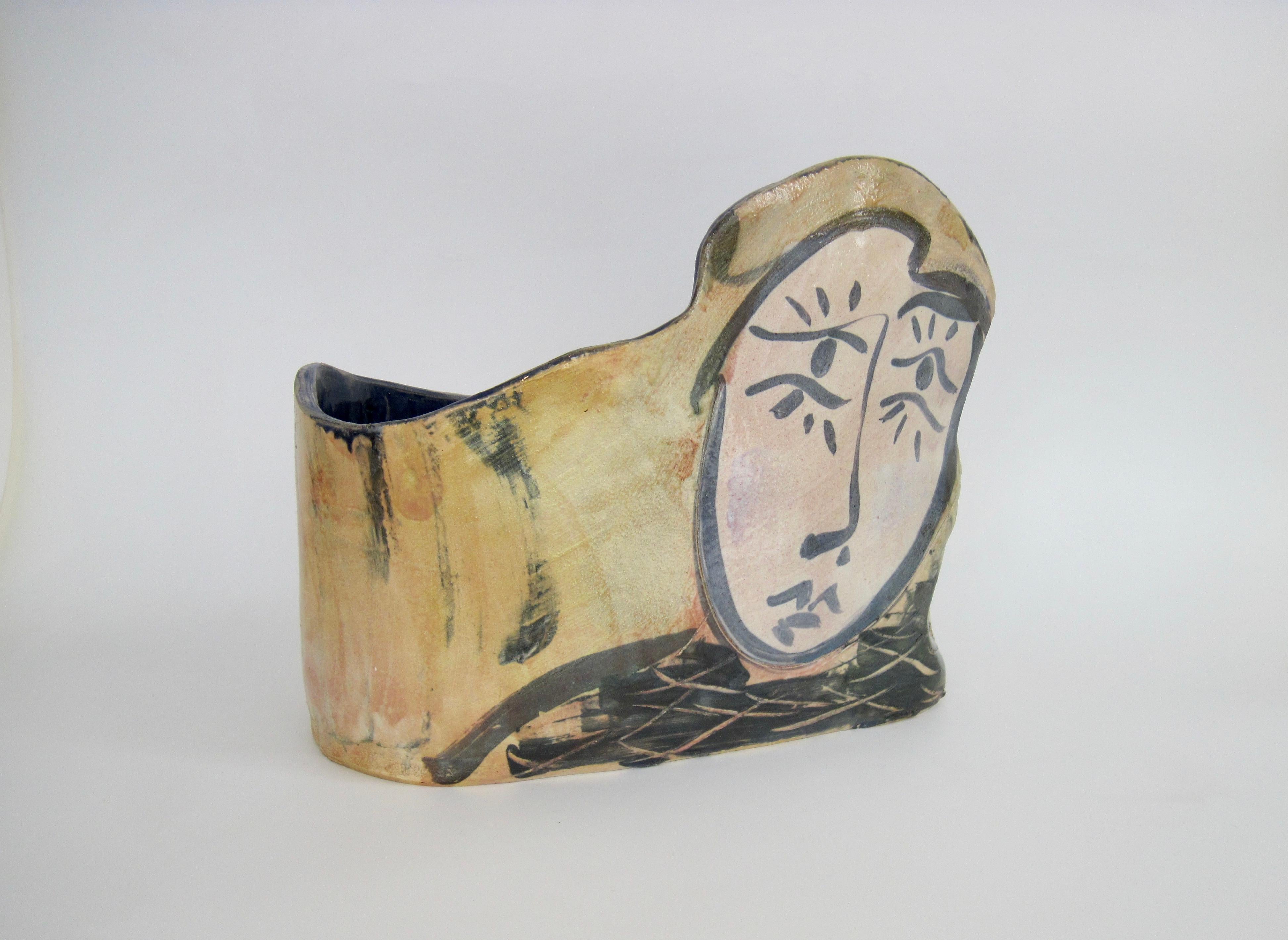 Hand signed studio constructed slab pottery after Picasso as a magazine holder, planter, or trash can. Could also be used for kindling next to a fireplace. The oblong shape has an earth tone exterior, blue and light skin tone face and incised