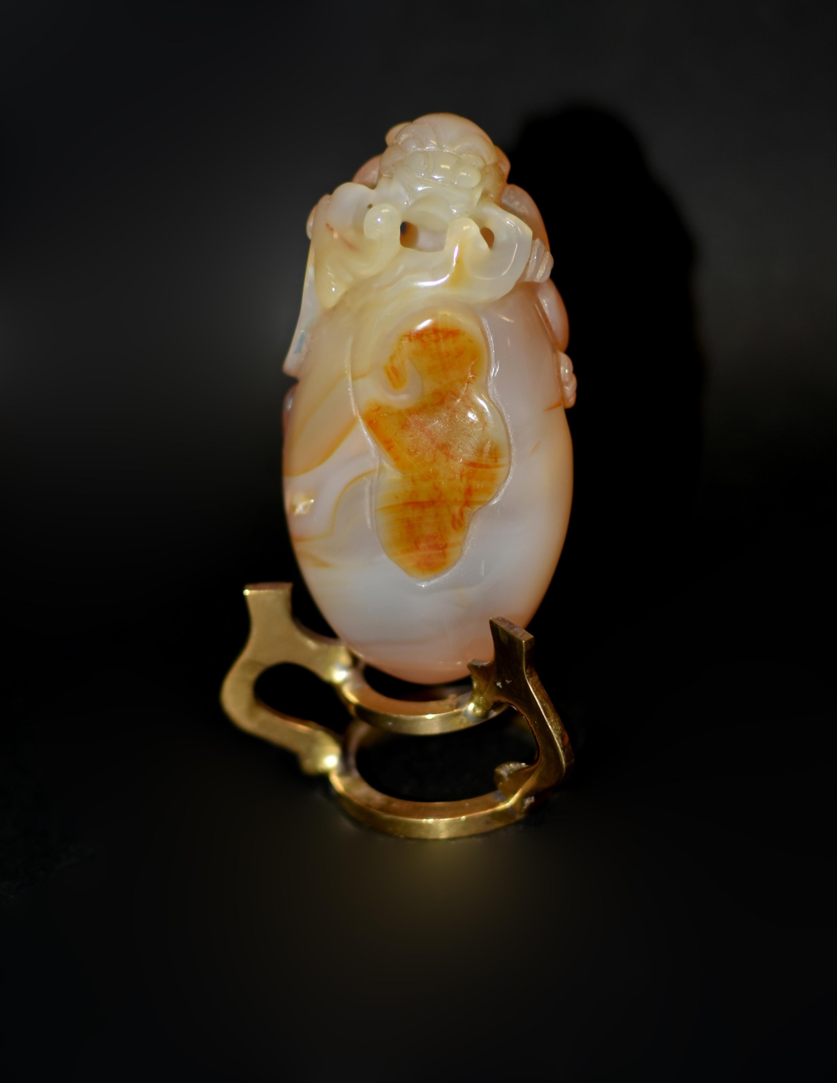 Cette exquise breloque à main, fabriquée en agate massive, capture l'essence de l'ancien symbolisme chinois. Un lion foo dog plein de vie est perché au sommet d'un rocher ovale, la bouche ouverte tenant un ruban de soie, la tête ornée de moustaches