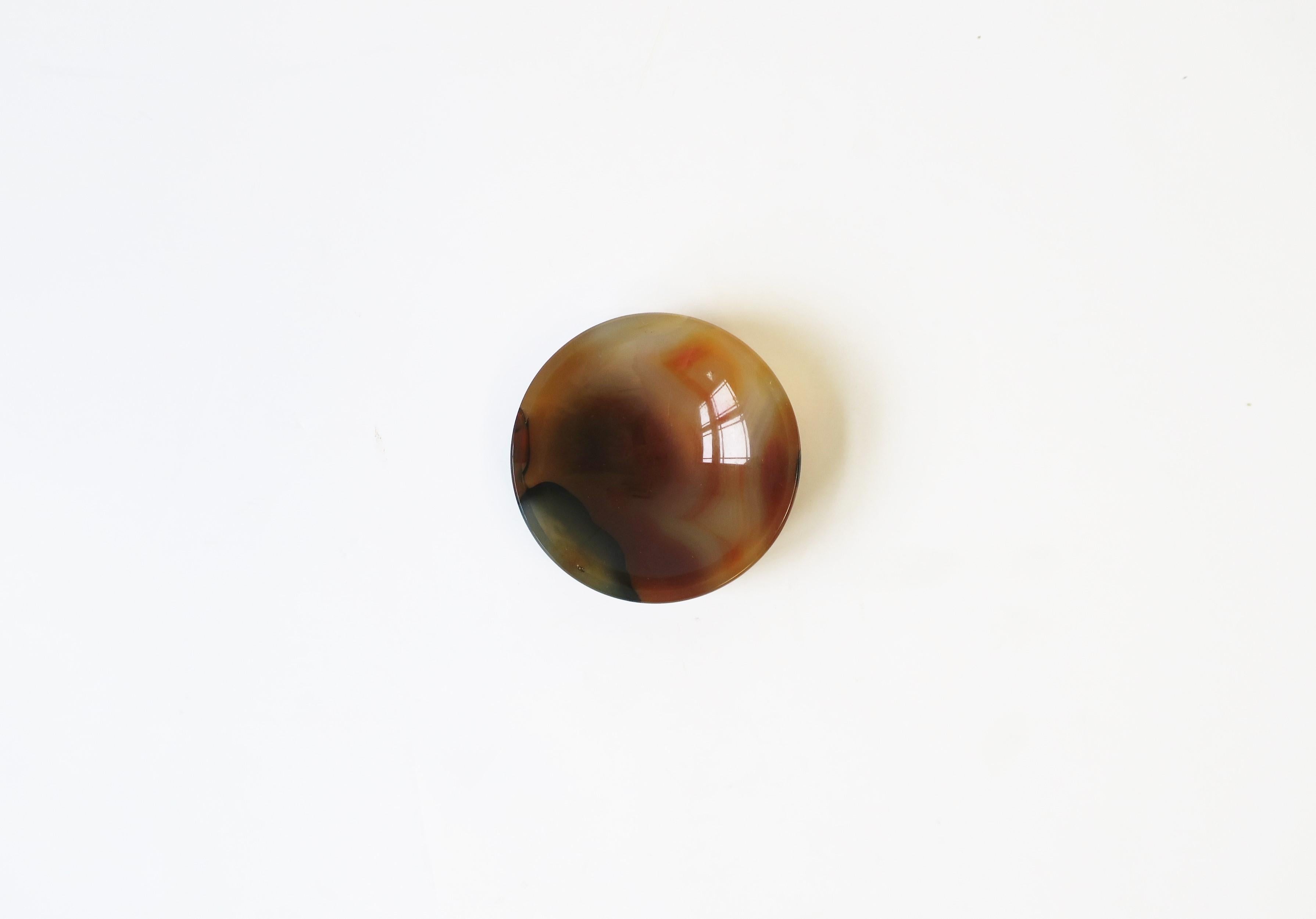A round polished agate jewelry dish, circa late-20th century. A great piece to hold jewelry (as demonstrated) or other items on a desk, vanity, nightstand table, dresser, etc. Dimensions: .75