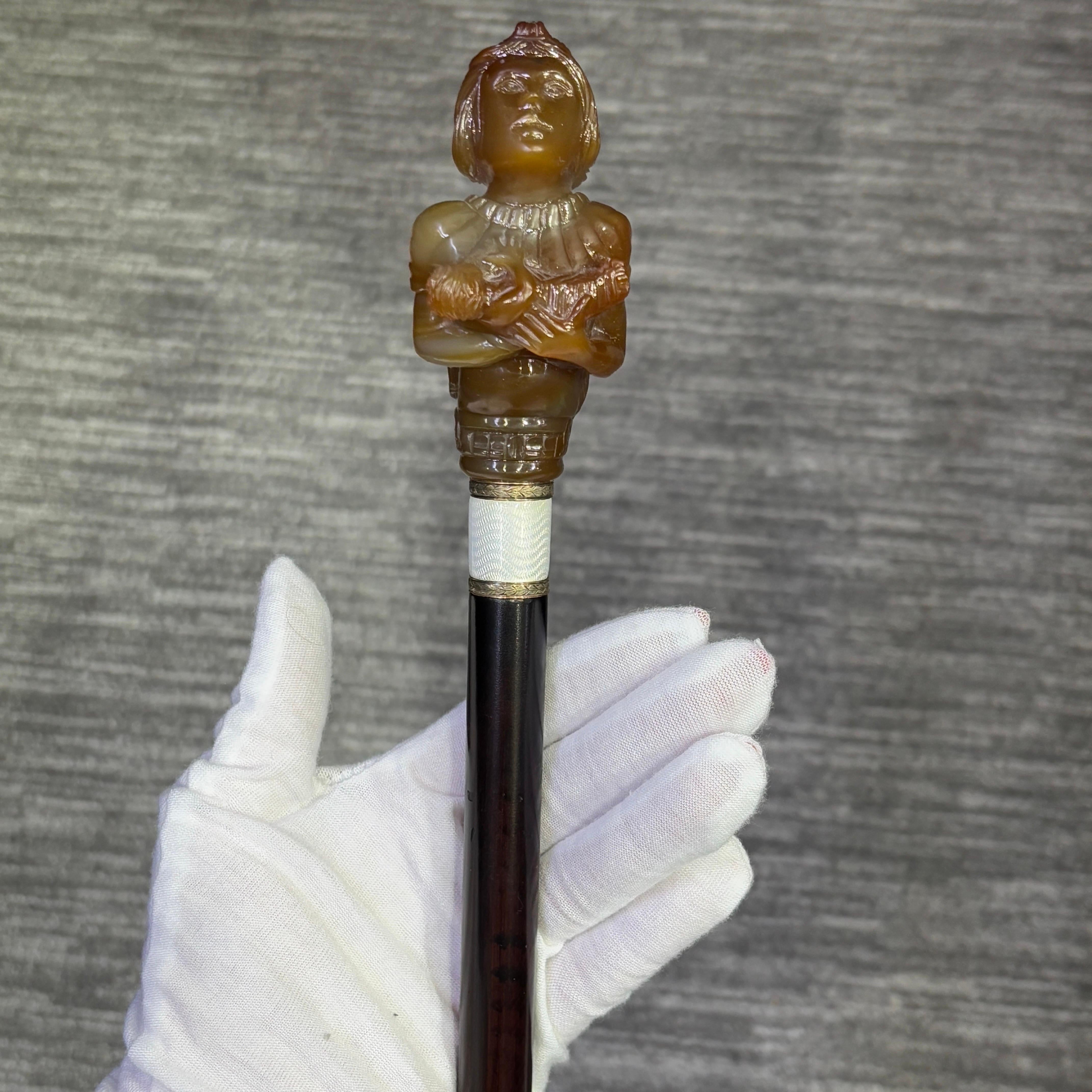 Canne d'allaitement en agate de la Néréide

Canne de la fin du 19e siècle représentant une néréide en agate sculptée allaitant un bébé, avec un collier en émail guilloché blanc,  et un manche en bois teinté avec une virole en métal.

Mesures :