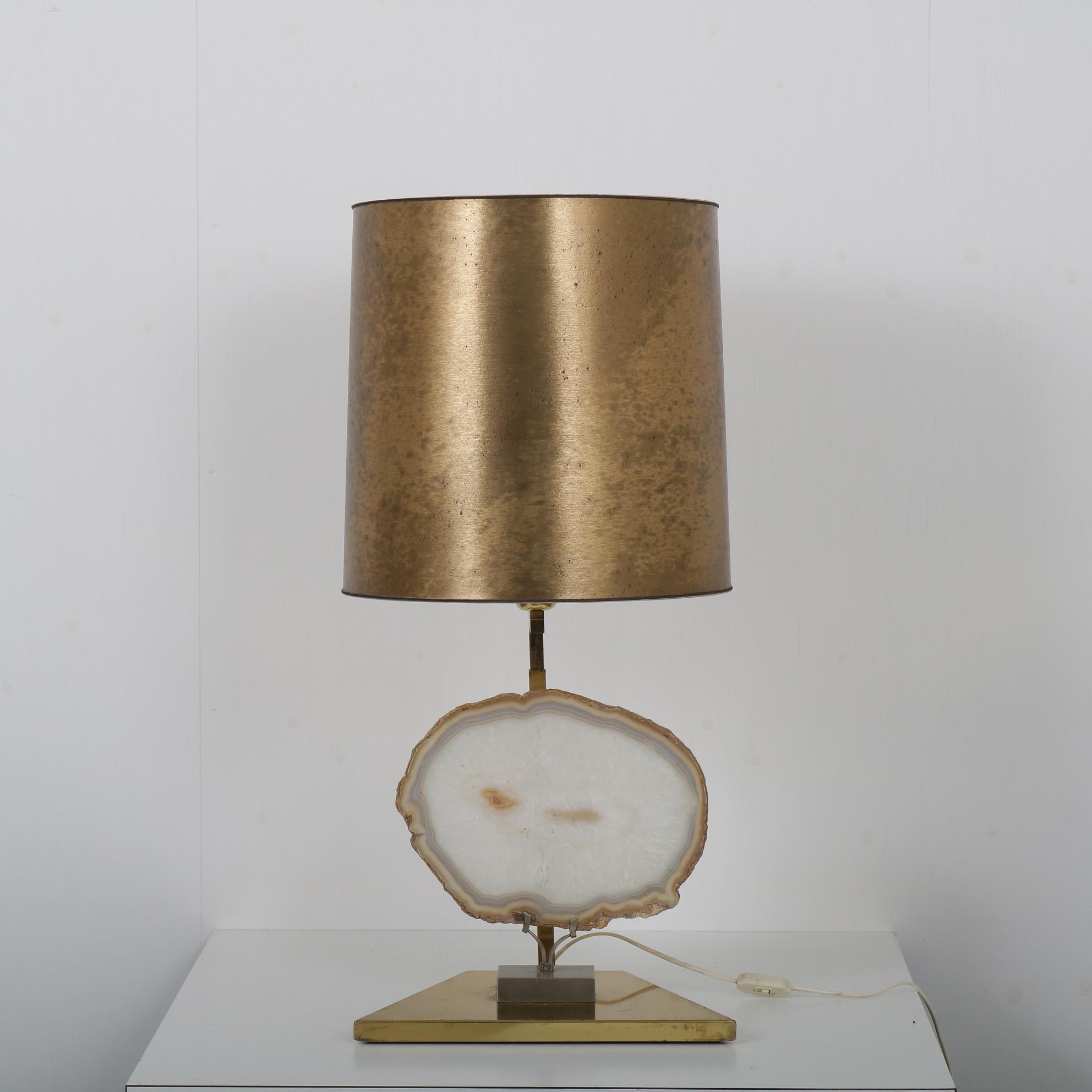 

An elegant table lamp with a big piece of agate stone (in the manner of Willy Daro), manufactured in Belgium around 1970.

The lamp has a beautiful brass base and a matching hood. The true eye-catcher is the stone made of rare agate in the base.