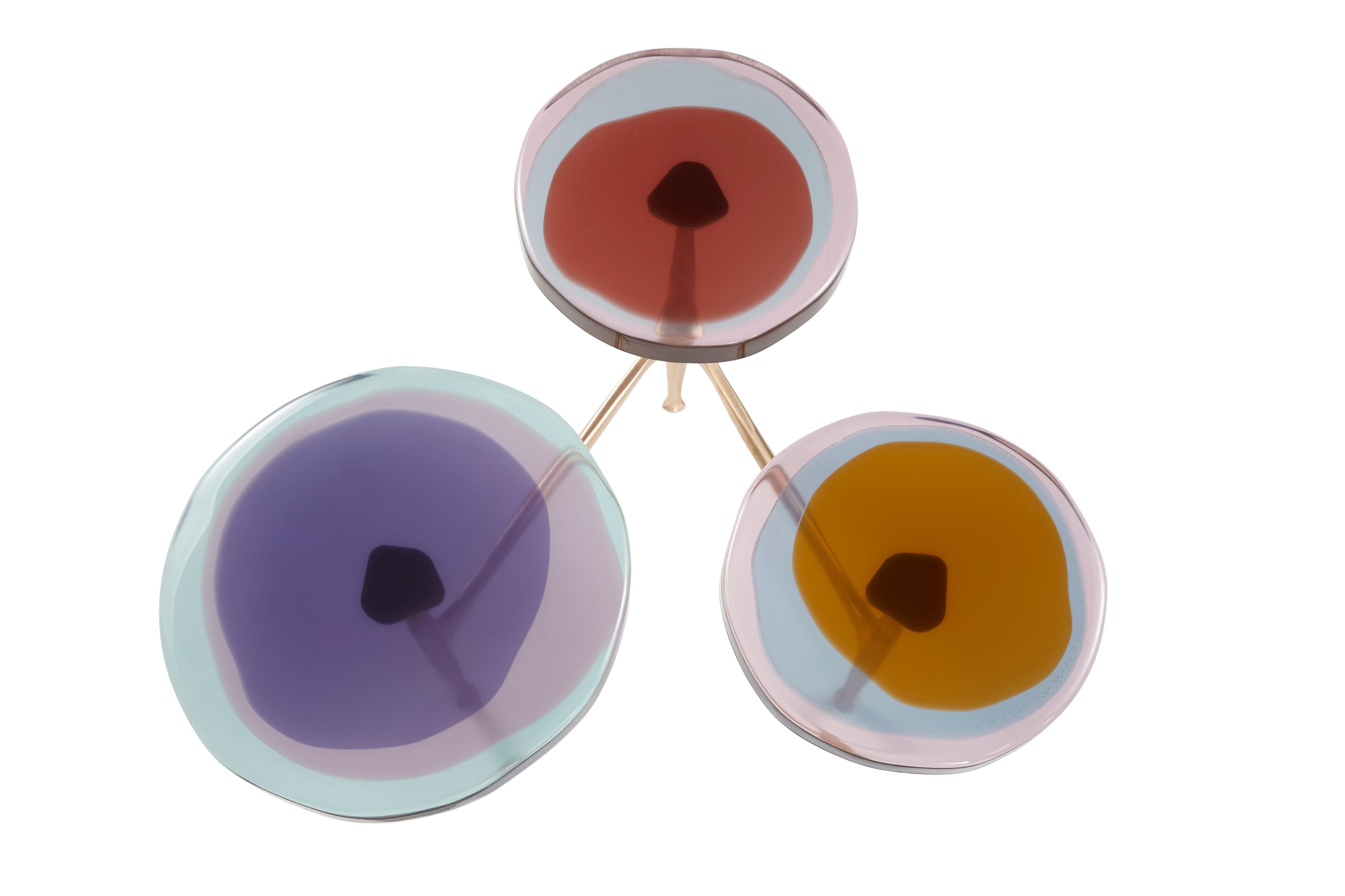Des grappes de fleurs sauvages ont inspiré la série de tables basses multi-tops Agatha, avec ses formes organiques et ses teintes irisées. Les plateaux circulaires irréguliers en résine époxy transparente sont encastrés dans un cadre en bronze à