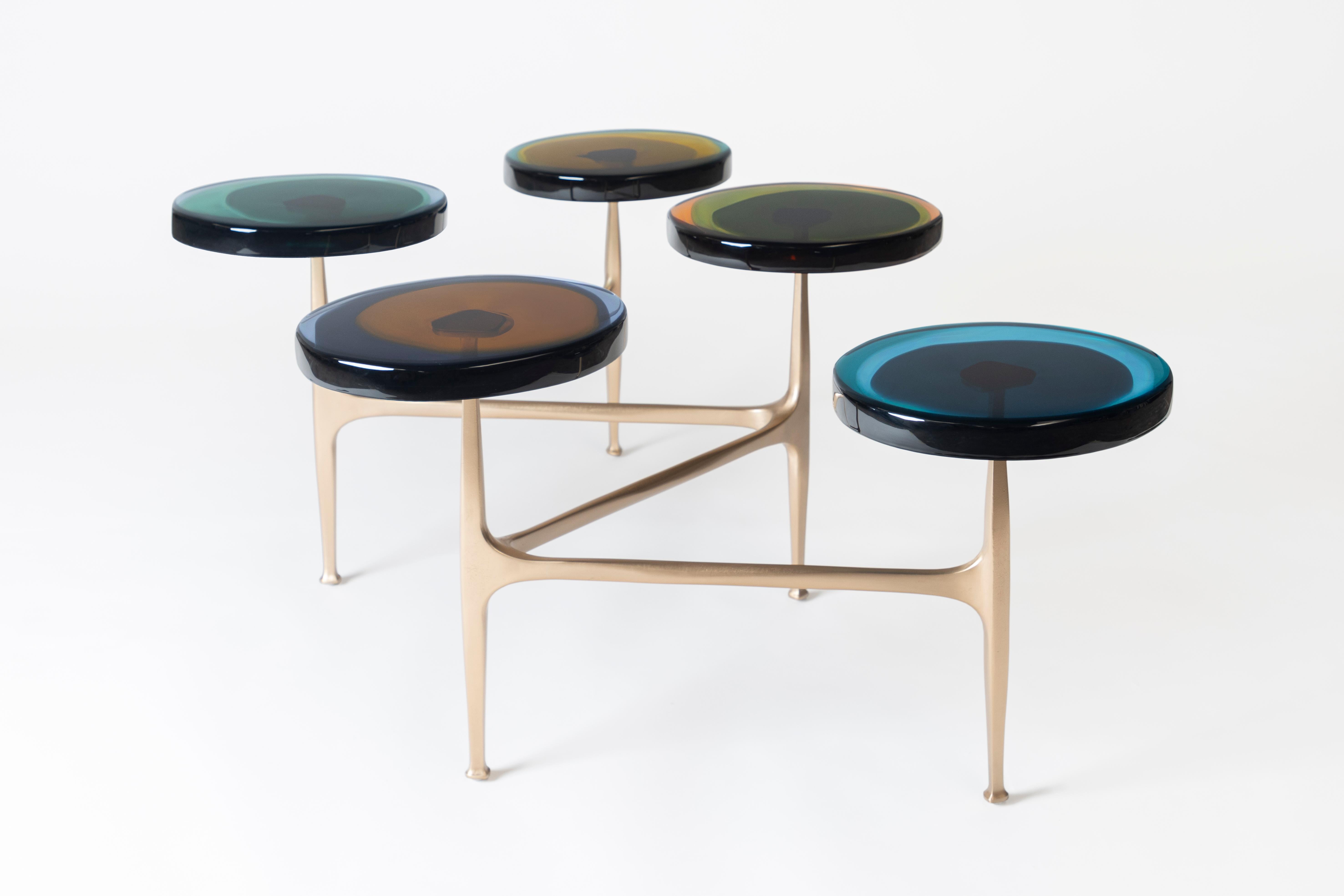Des grappes de fleurs sauvages ont inspiré la série de tables basses multi-tops Agatha, avec ses formes organiques et ses teintes irisées. Les plateaux circulaires irréguliers en résine époxy transparente sont encastrés dans un cadre en bronze à