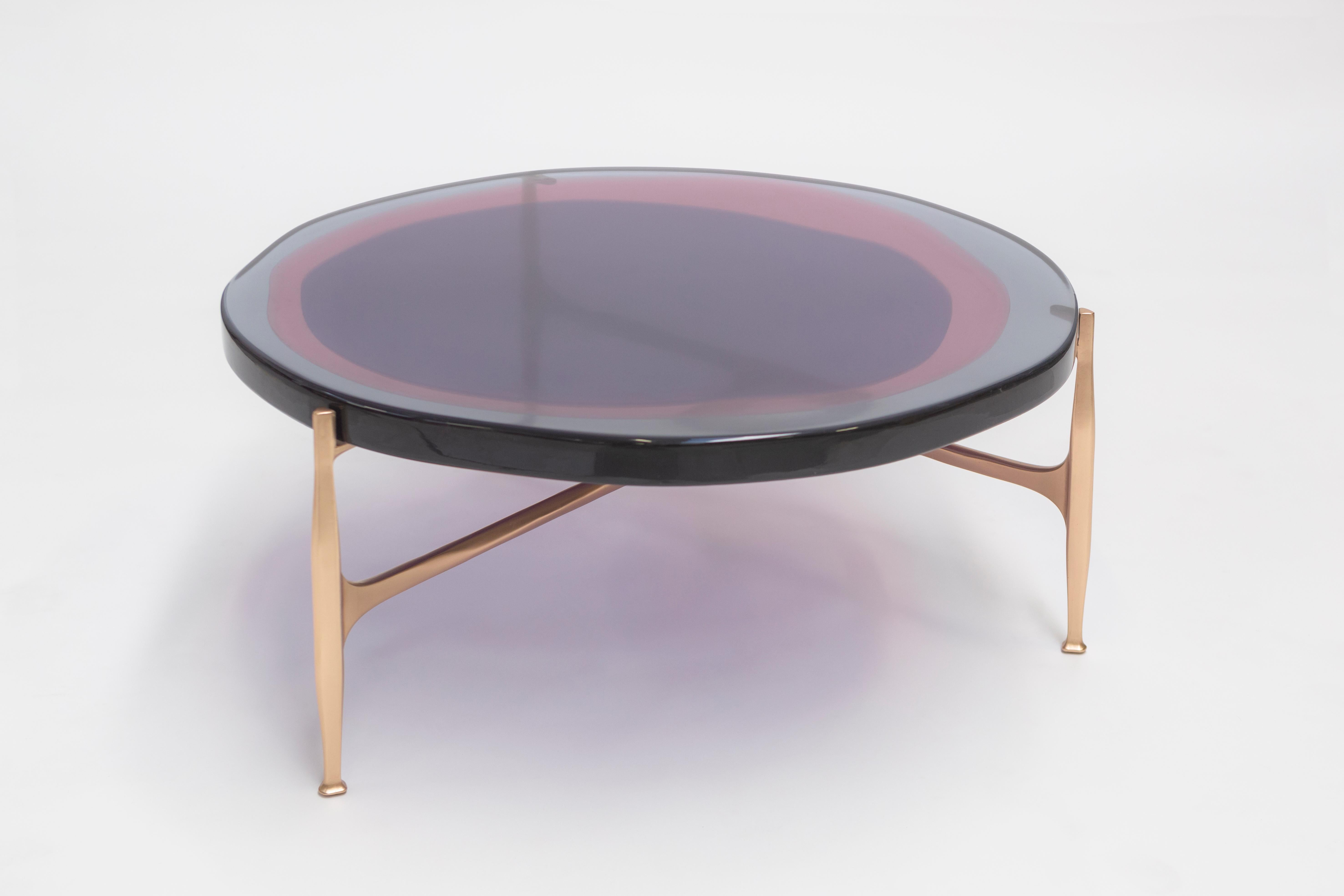 Mit einer unregelmäßigen, runden Platte aus transparentem und farbigem Harz, die in einem versetzten Muster auf einem Bronzegestell angeordnet ist, spielt dieser Tisch mit dem Licht. Die Herstellung erfolgt in einem speziellen Harzgießverfahren. Das