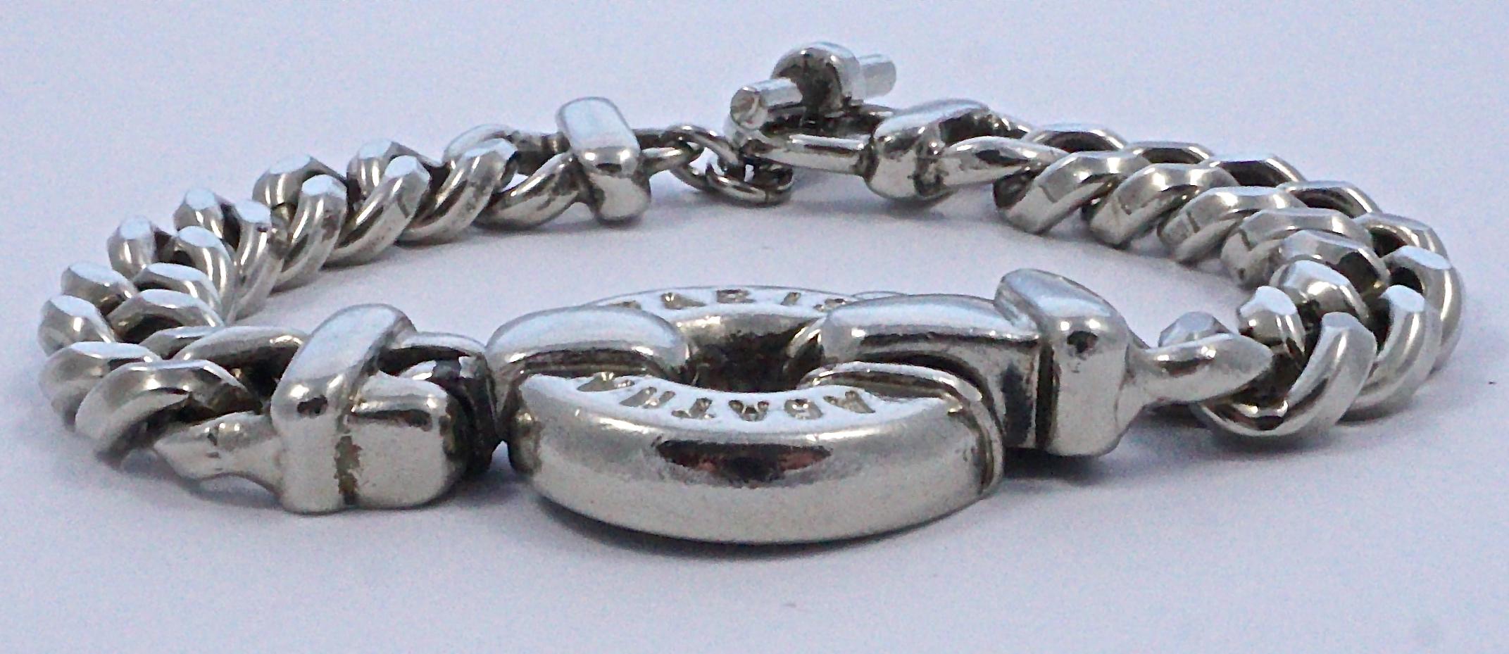Le bracelet Agatha Paris est un bracelet à maillons en chaîne de couleur argentée, avec un médaillon rond et épais estampillé Agatha Paris, et un fermoir à boucle. La longueur est de 20,5 cm, la largeur de 1 cm, et le diamètre du médaillon est de