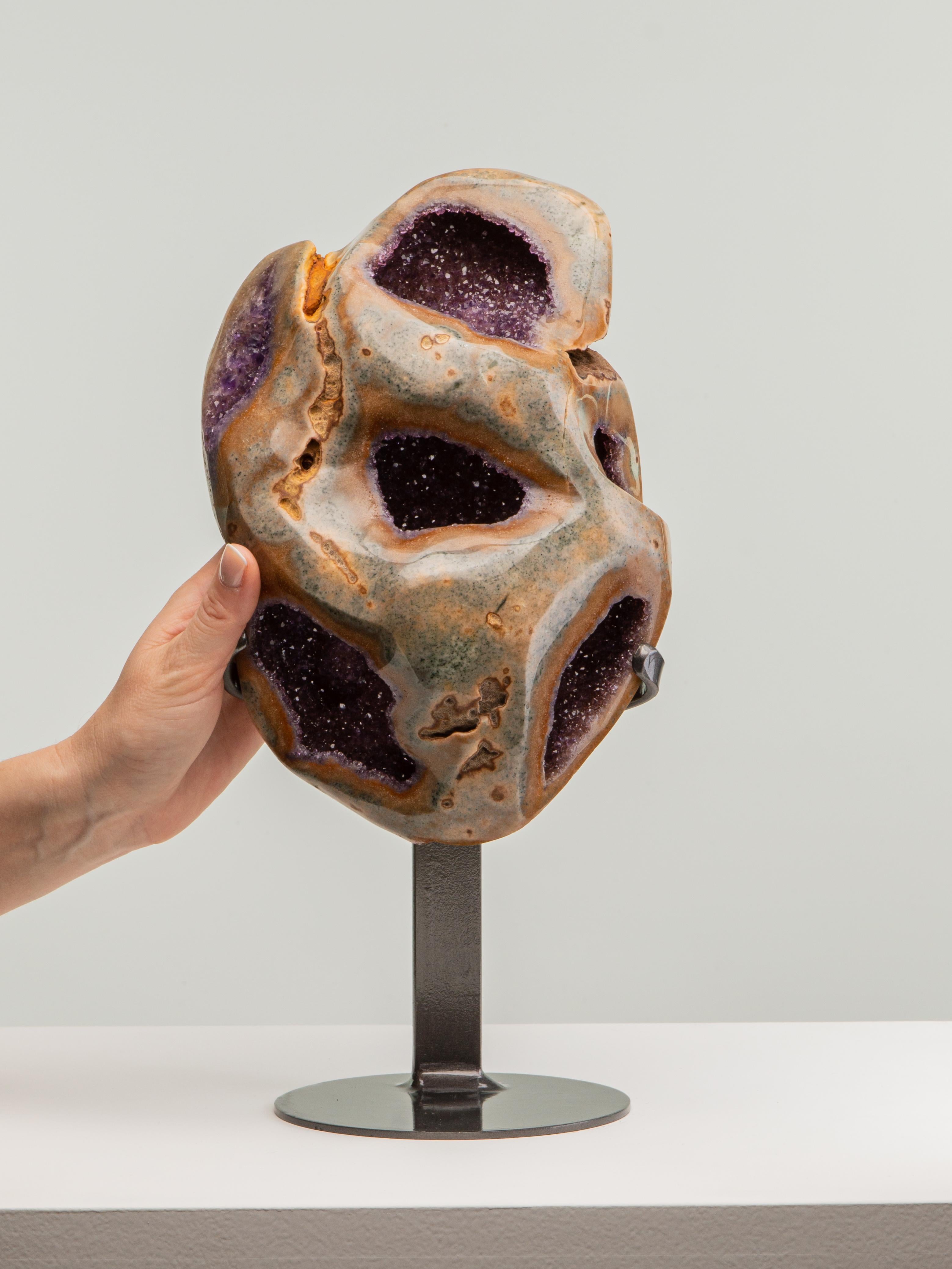 This heavily agatiised medium sized geode contains 6 “windows” from
which the beautiful amethyst interior can be appreciated. A spectacular
display piece.

This piece was legally and ethically sourced directly in the prestigious mines of