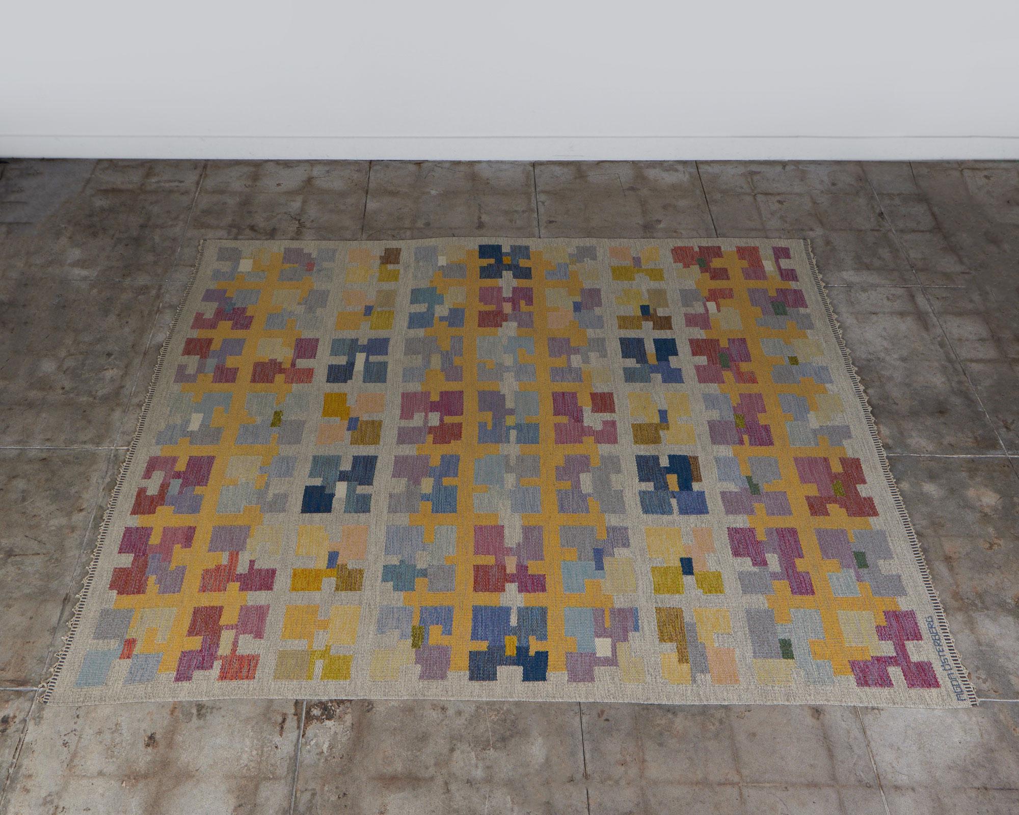 Tapis tissé à plat par la designer suédoise Agda I.C., c.1950, Suède. Le motif carré abstrait du tapis donne une impression de mouvement et de texture. Les tons sourds de l'aquarelle (jaune, bleu et rose) confèrent une certaine douceur à l'œuvre. Le