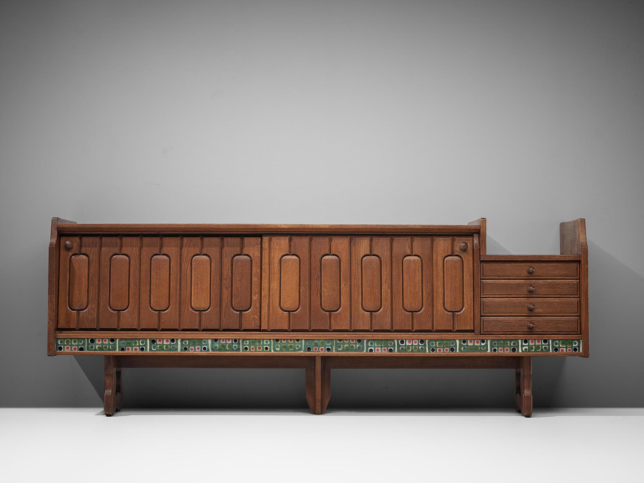 Guillerme et Chambron, sideboard model Simon, oak and ceramic, France, 1960s. 

Credenza in oak by French designers Guillerme & Chambron. This sideboard is equipped with two sliding-doors and a set of drawers. The front of the sideboard is