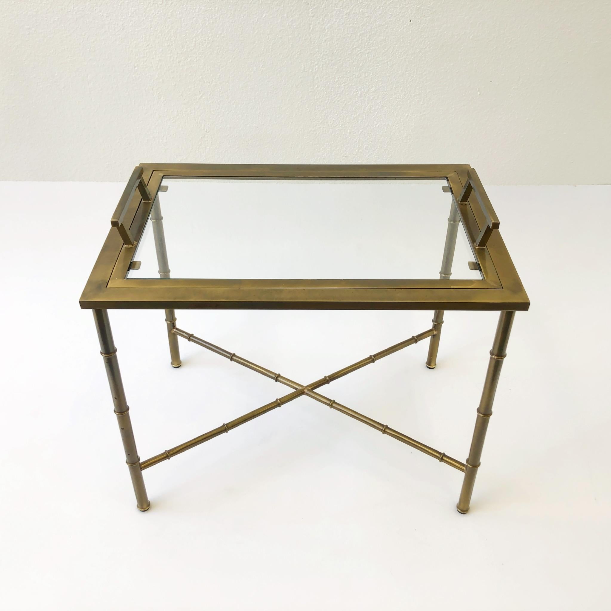 1970s aged brass and glass Faux Bamboo tray table by Mastercraft. The table is in original condition so it shows some age(see detail photos). 

Dimension: 24.13” wide 16.63” deep 19” high to tabletop 21.25” high to handlers.