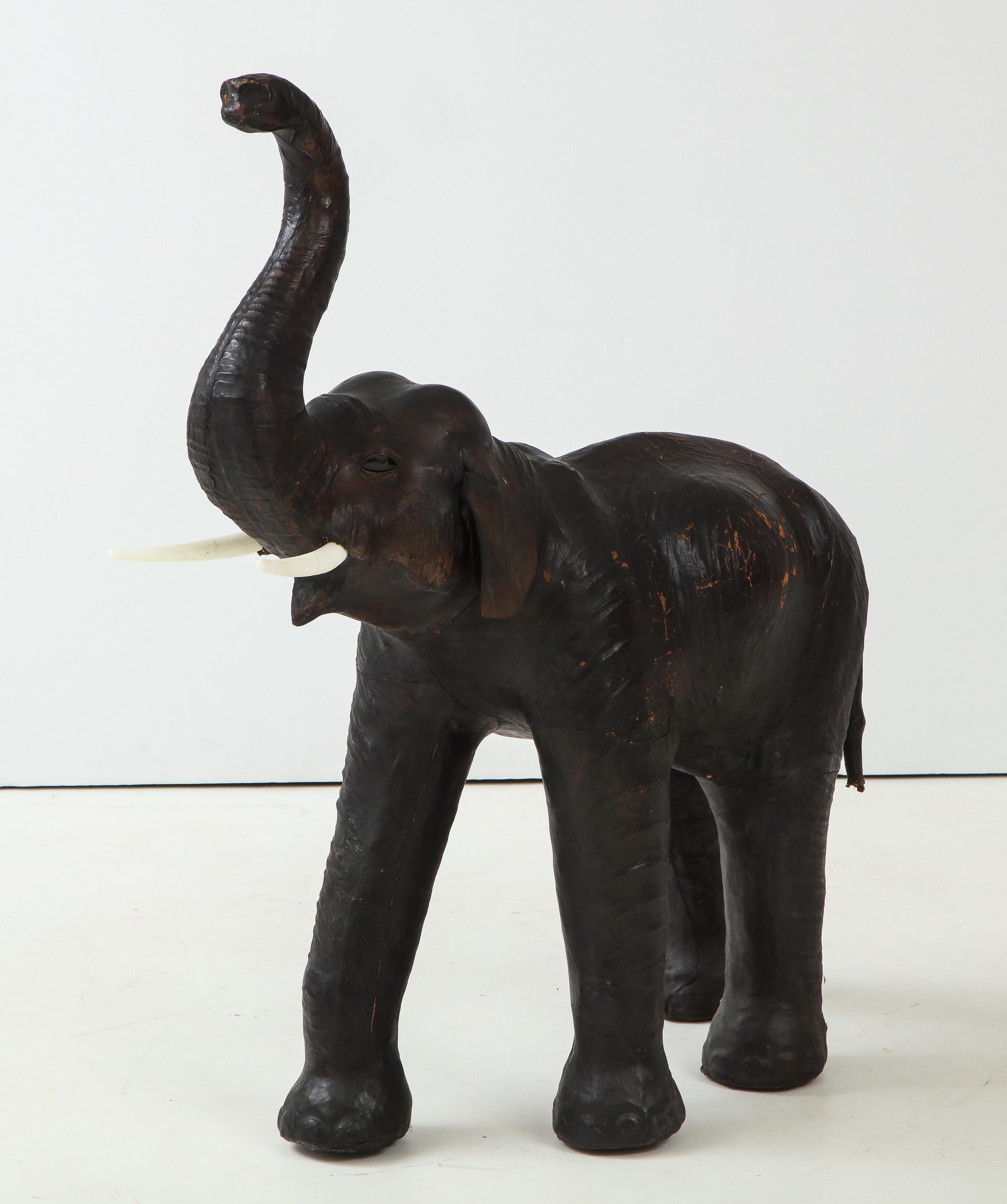 Handcrafted leather elephant statue with glass eyes and white wooden tusks.