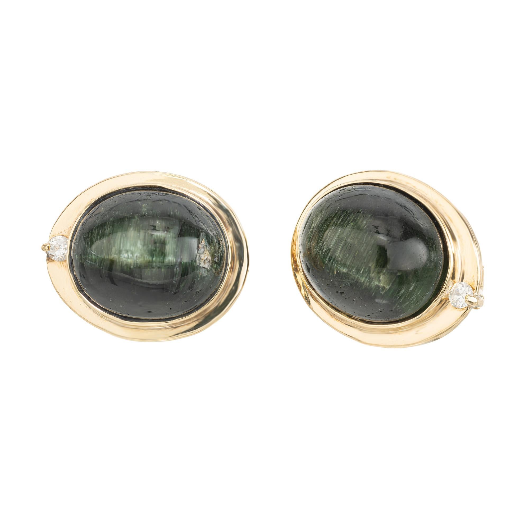 1960's Oval green Tourmaline Cat's Eye and Diamond gold clip post earrings. These captivating earrings are a harmonious blend of nature's finest and artisan craftsmanship. Each earring features an alluring cabochon oval 7.00ct green cat's eye