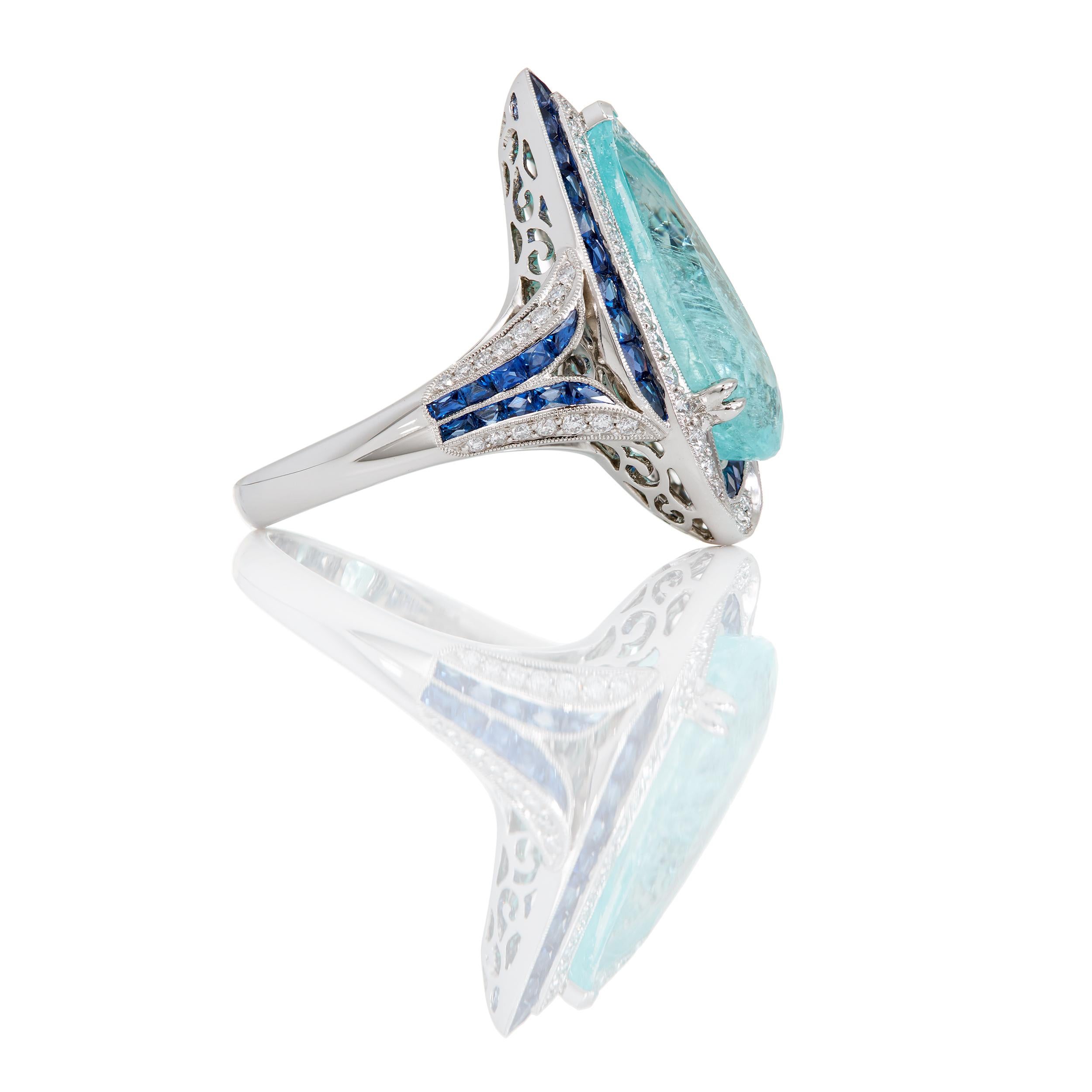 Des saphirs bleus de Ceylan et des diamants entourent gracieusement cette spectaculaire tourmaline Paraiba de 5,39 carats, de forme allongée et en poire.  Cette bague unique en son genre a été conçue et fabriquée à la main avec un ensemble de