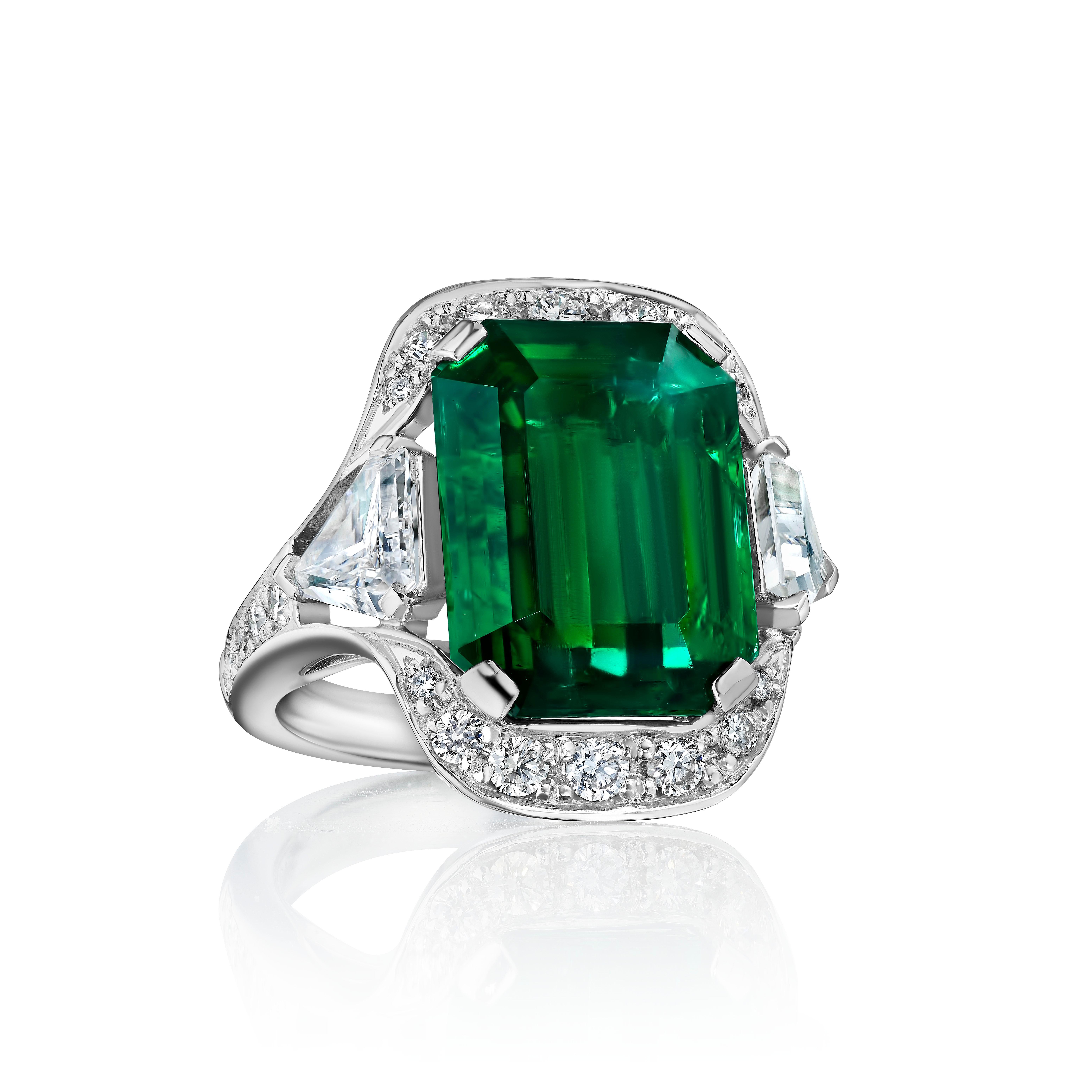 Centered upon a Emerald Cut Emerald weighing 10.08 Carats, flanked by Step Cut Trapezoid Shaped Diamonds weighing 1.43 Carats. Certified by AGL.

Flanked by shield Cut Diamonds weighing 1.64 Carats and embellished with 22 Round Diamonds weighing