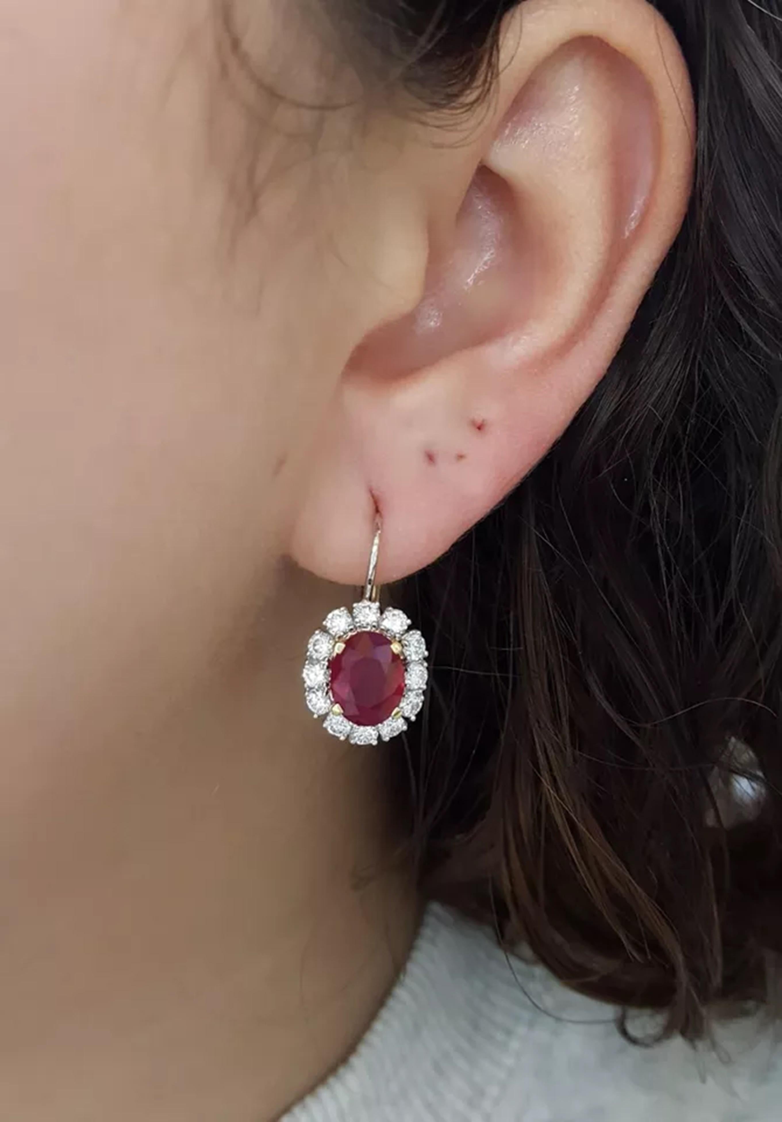 18K White and Yellow Gold Earrings featuring a total weight of 6.55 ct with Natural Oval Cut Burma Pigeon Blood Rubies and a Diamond Halo.

The earrings showcase 2 Natural Oval Cut Rubies in a vivid Pigeon Blood red hue, weighing 5.05 ct with minor