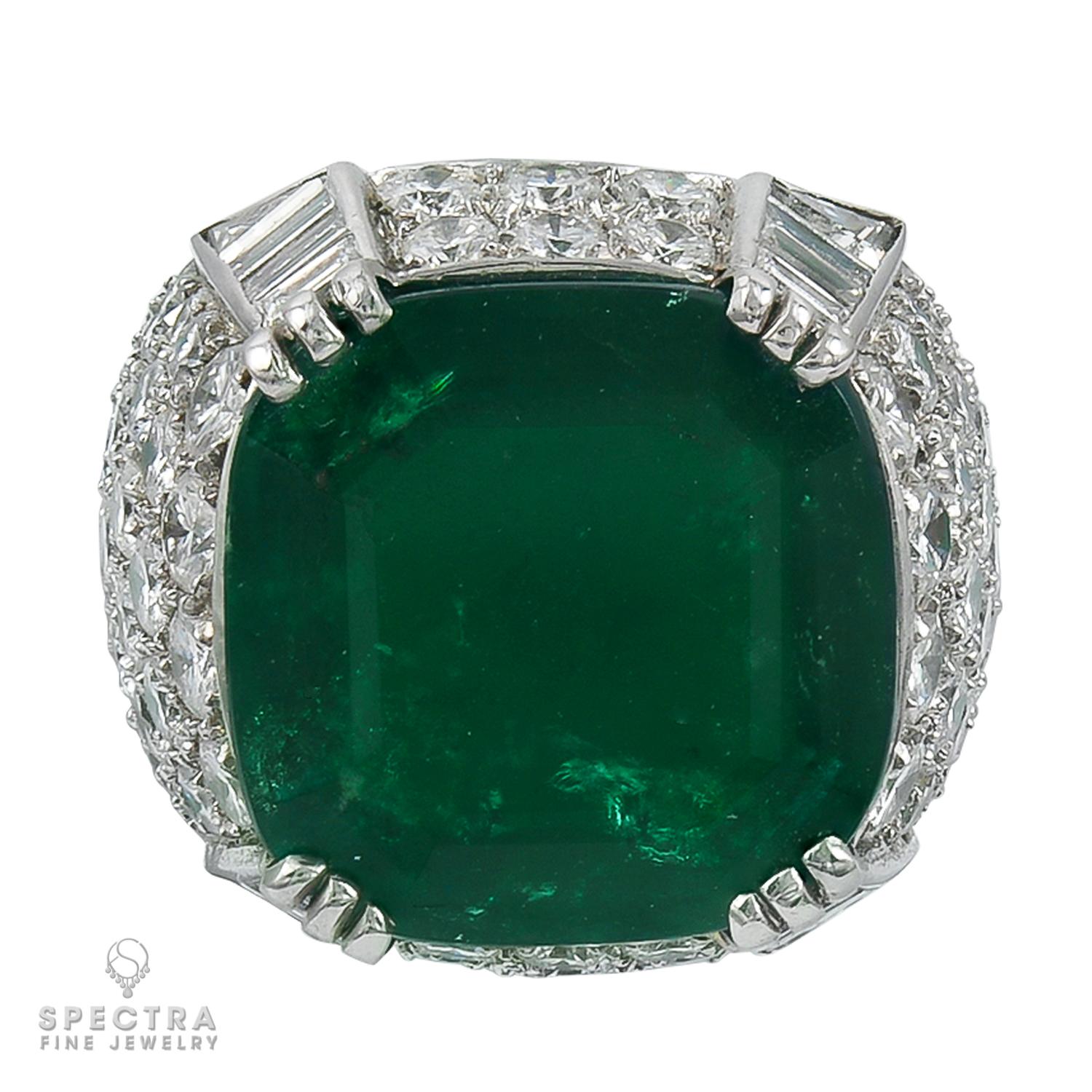Behold the spectacular 2018 creation from Spectra Fine Jewelry—a Platinum Emerald and Diamond Cocktail Ring that captivates with its allure. The centerpiece is an awe-inspiring cushion-cut Colombian emerald weighing around 11.38 carats, certified by