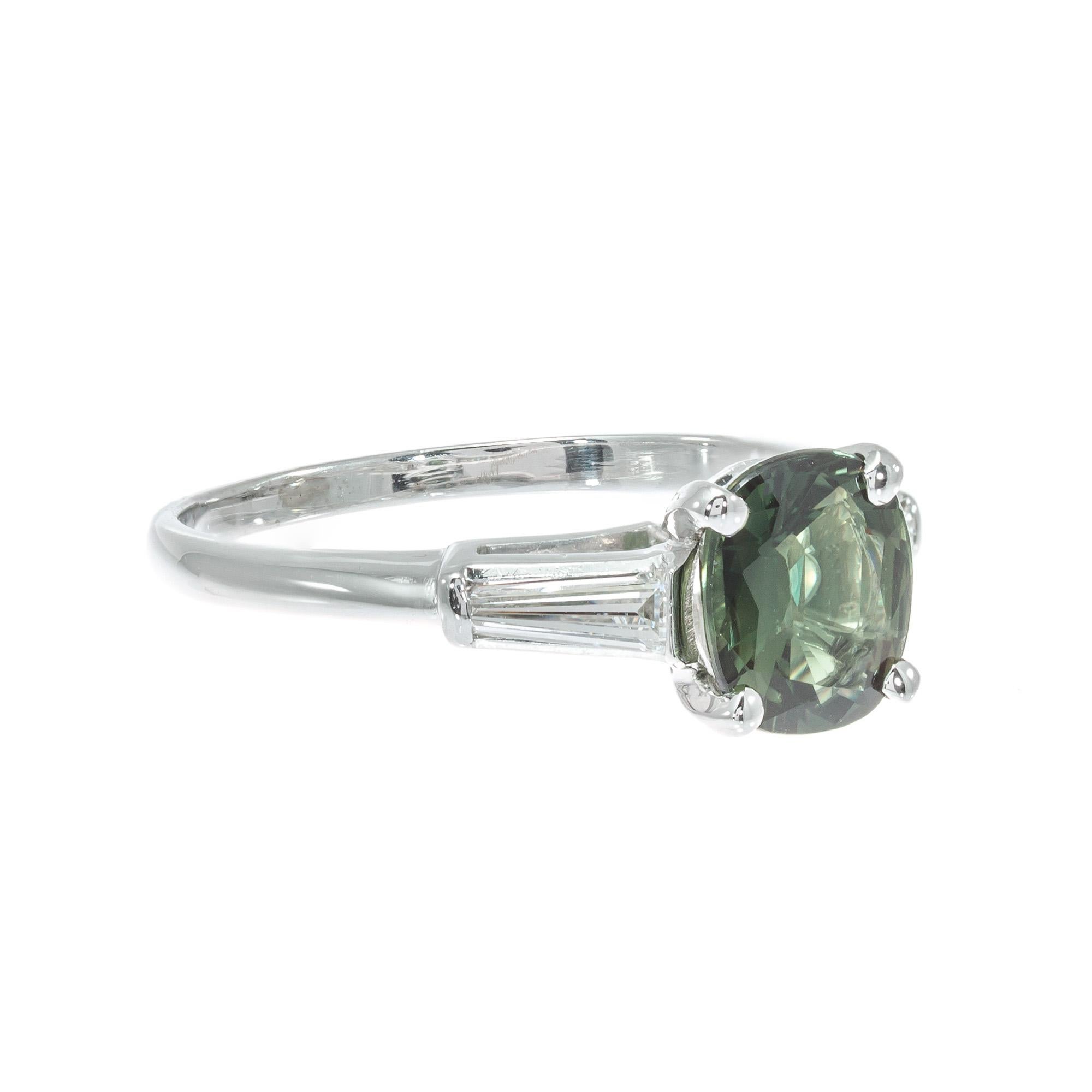 Vintage green sapphire and diamond engagement ring. oval sapphire center stone set in a original handmade platinum three-stone setting with two tapered baguette accent diamonds.  AGL Certified as natural color simple heat only.

1 cushion cut