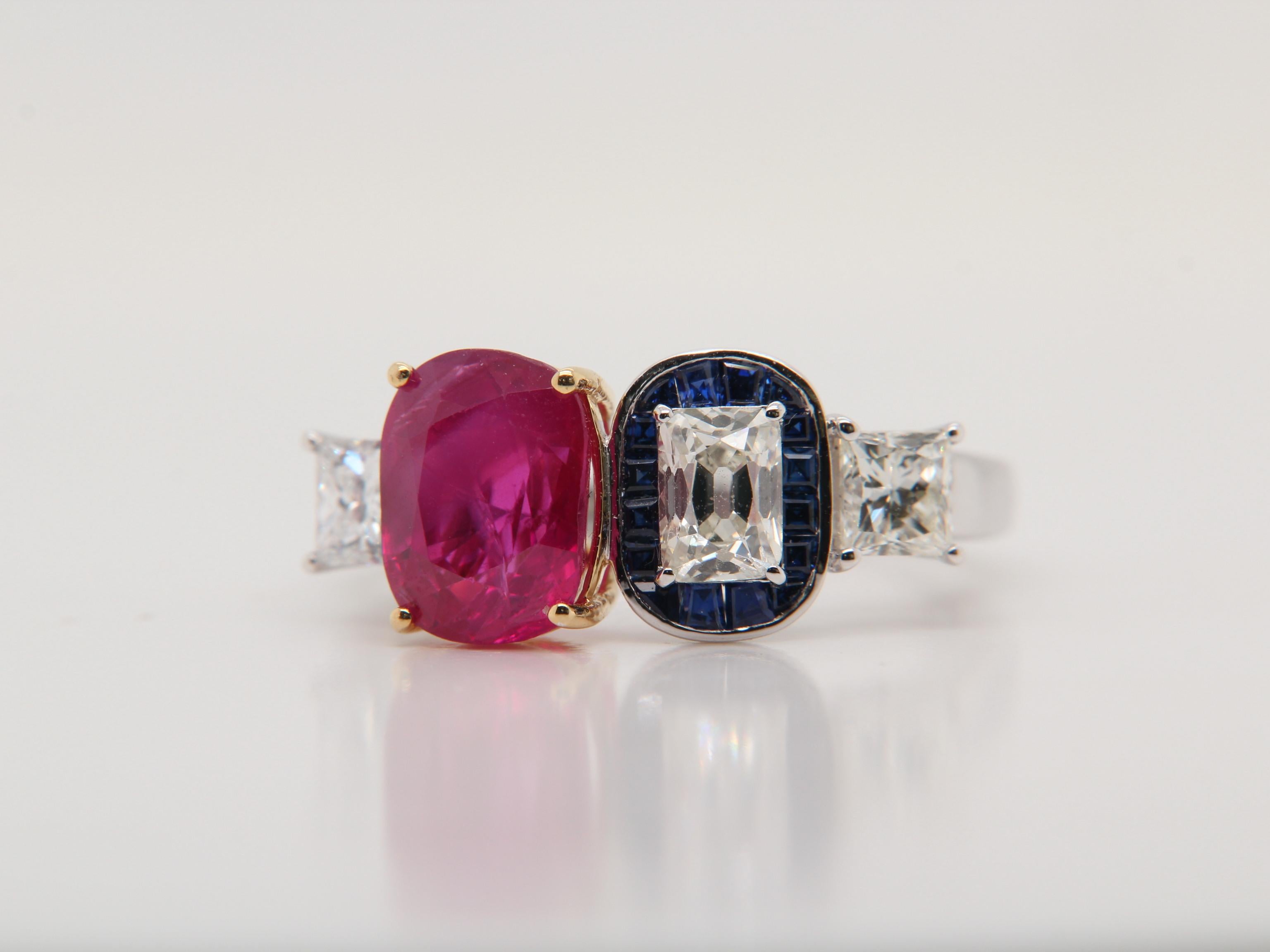 A new 3.03 carat Burmese ruby ring made in 18 Karat gold. The ruby is certified by AGL (Thai) as natural, unheated, 'Purplish-Red', and from the mine 'Mogok'. The total diamond weight is 1.12 carats, total blue sapphire weight is 0.27 carats and the