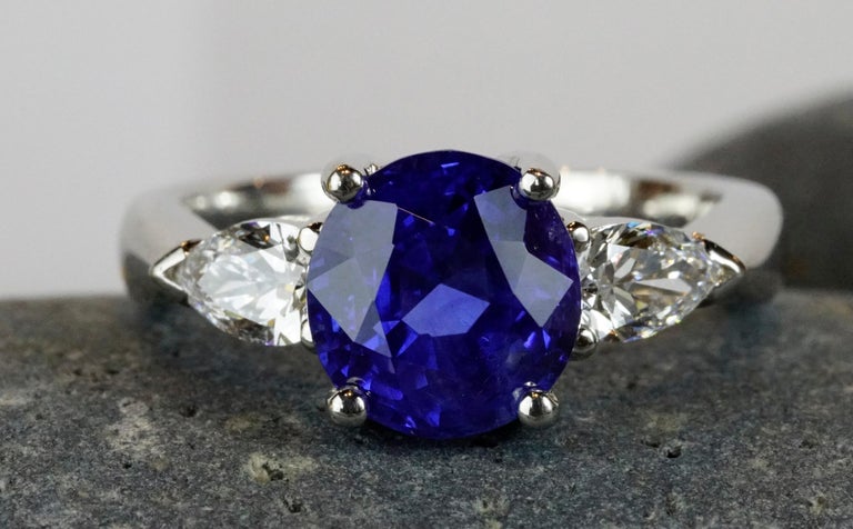 Three stone ring set with a natural un heated cushion shape 4.21 Carats sapphire (royal blue) with two natural pear shaped diamonds 0.62 carats total weight , AGL certified diamonds are GIA certified. 
Stunning classic and a rare staple to add to