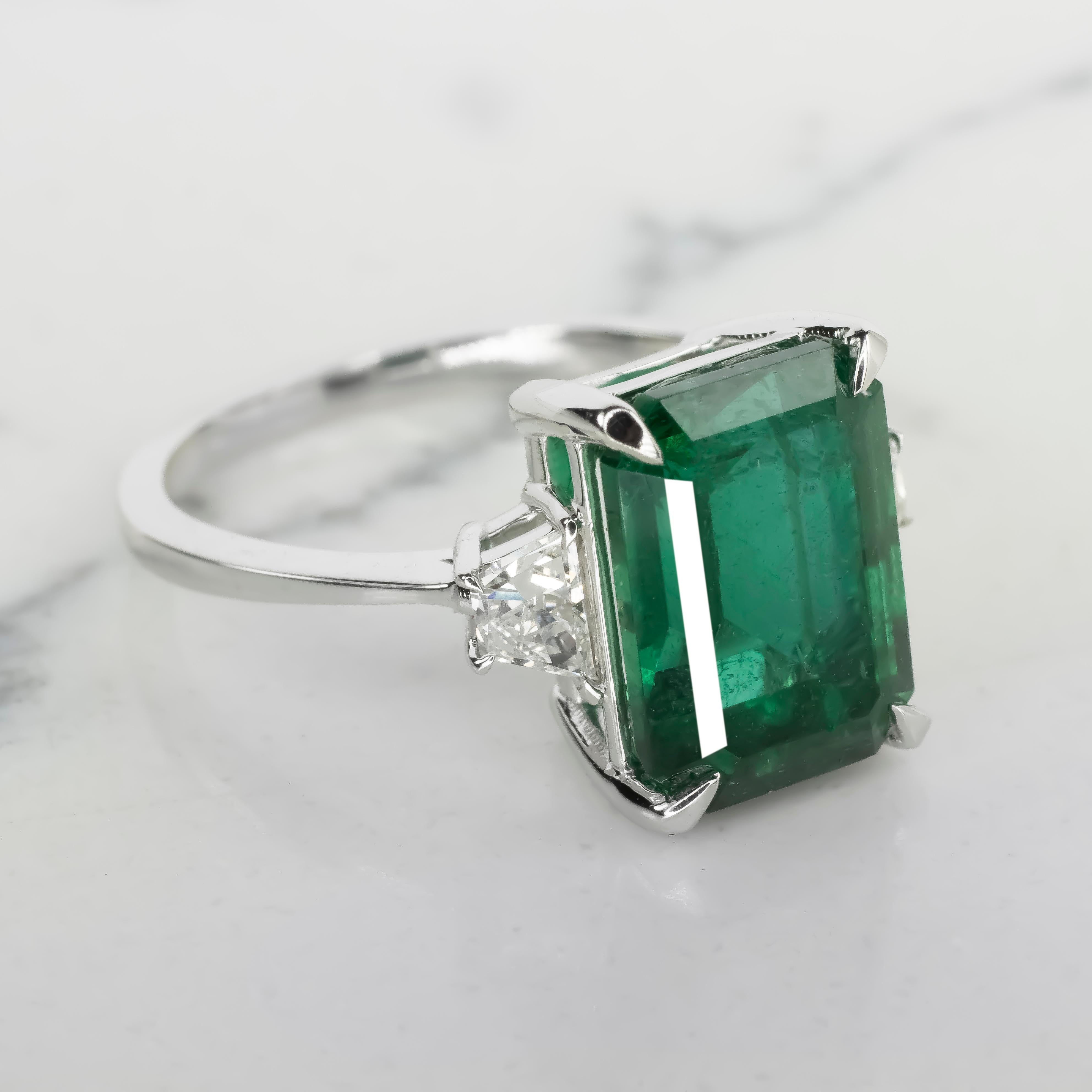 This exquisite ring features a 5.71-carat natural emerald from Zambia, certified by AGL. The emerald is emerald-cut, measuring 11.46 x 9.40 x 7.26 mm, and displays a rich green hue with minor traditional oil treatment for clarity enhancement.

Set