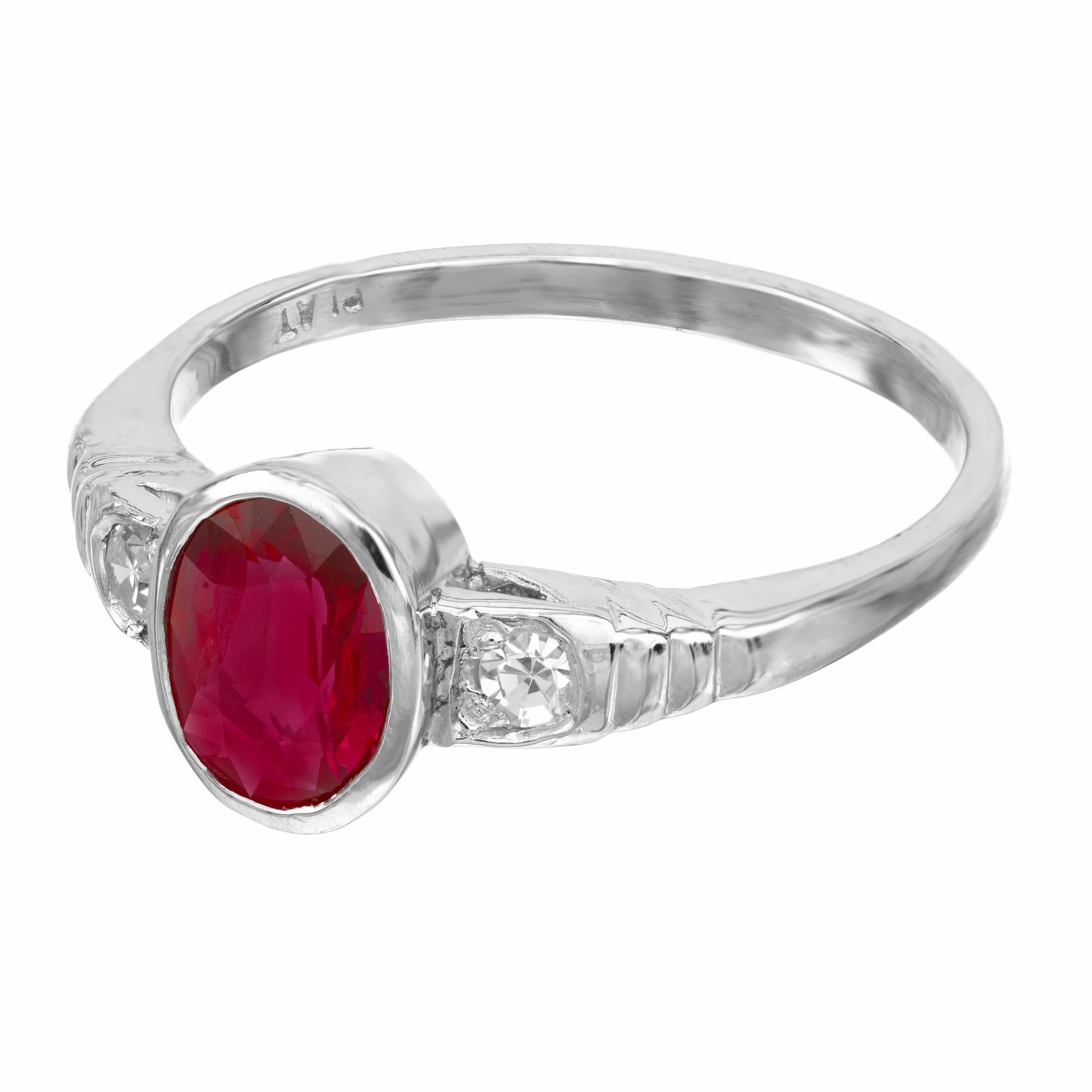 1940's late Art Deco ruby and diamond three-stone engagement ring. At the center is a .80ct oval bezel set ruby, mounted in a simple platinum setting. On each side of the ruby is one single cut accent diamond. The ruby is certified by the AGL as