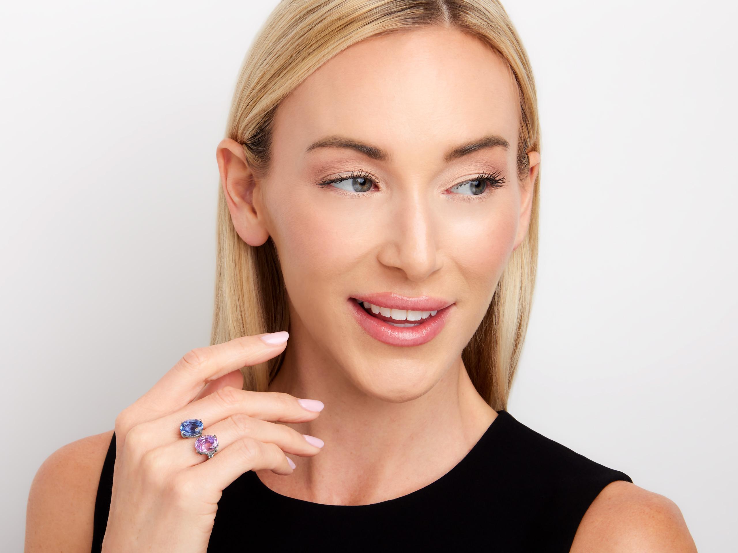 Ein auffälliger Bypass-Ring aus Platin mit einem 8,02-karätigen rosa Saphir und einem 7,05-karätigen blauen Saphir, beide von AGL als unerhitzt zertifiziert. Die Saphire werden von ca. 0,50 Karat Diamanten auf dem Schaft elegant akzentuiert und