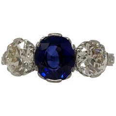 Dreisteiniger Ring mit AGL-zertifiziertem blauem Saphir im ovalen gemischten Schliff und weißem Diamanten