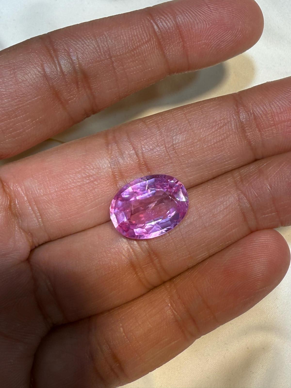 Zaffiro Padparadscha ovale da 10 carati certificato AGL. Questo raro tesoro si distingue non solo per le sue dimensioni impressionanti, ma anche per la sua accattivante tonalità: emana un delicato equilibrio di rosa tenue, con sottili accenni di