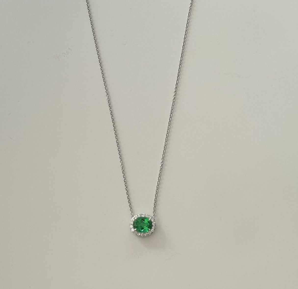 Realizzata a mano in platino, questa squisita collana con pendente presenta un paraiba verde naturale di forma ovale da 1,46 carati circondato da un'aureola di diciotto diamanti rotondi per un totale di 0,18 carati, colore GH, purezza VS. Il paraiba