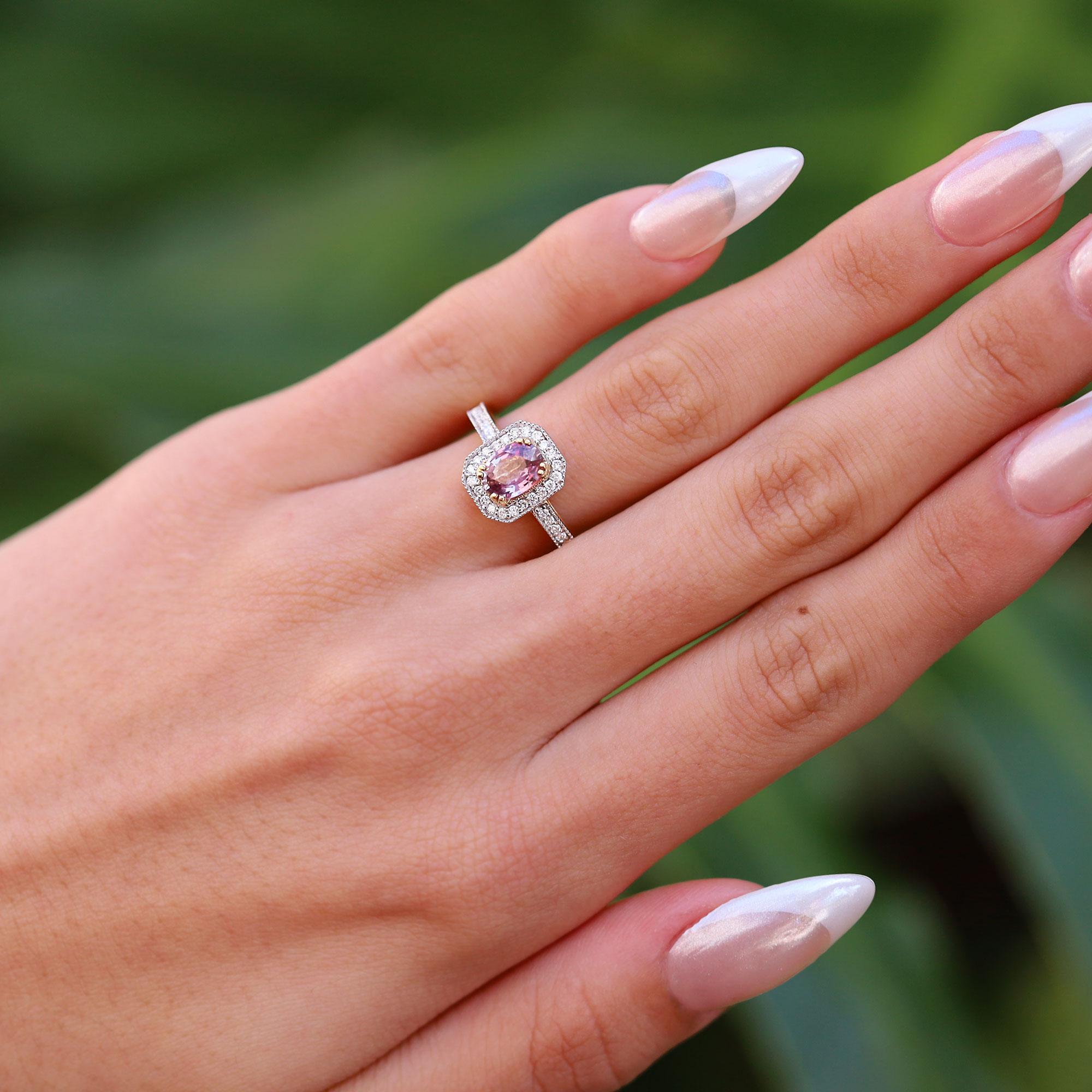 Une bague de fiançailles en saphir unique, centrée sur un magnifique saphir Padparadscha. Ce saphir naturel, qui provient du sanskrit et signifie fleur de lotus, est facetté et poli de manière experte et brille d'une couleur rose orangée lustrée.