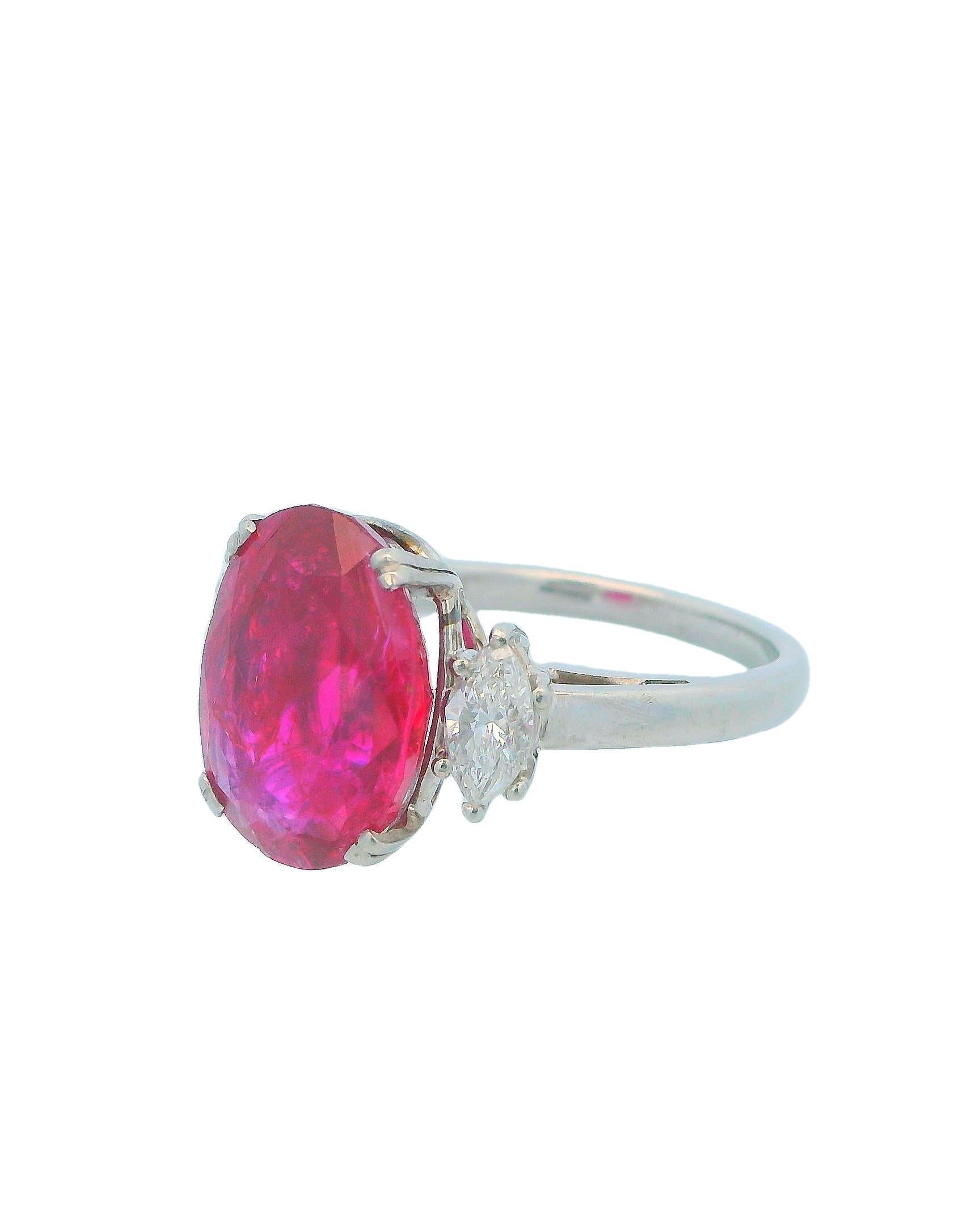 The 1970s Ruby and Diamond Ring is a stunning piece that beautifully captures the era's elegance and style. At its center is a captivating 7.25-carat cushion-cut ruby, which exhibits a deep, vibrant red color that draws the eye. Surrounding the ruby