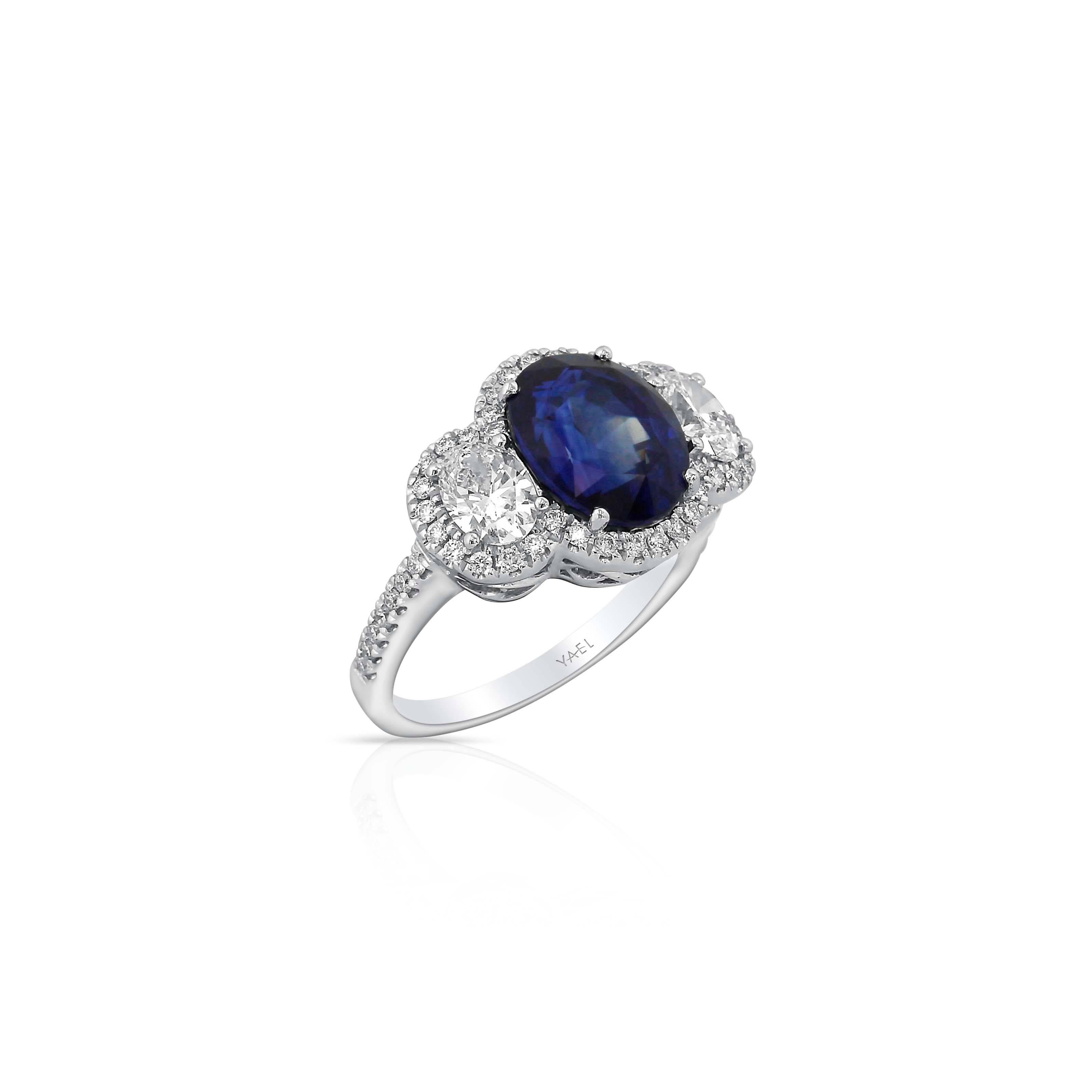 This three stone ring centers a magnificent sapphire between two well matched diamonds, the central motif surrounded by a modified halo to more strongly unify the parts into a sparkling whole. The ring is finished with diamond-set shoulders.

AGL