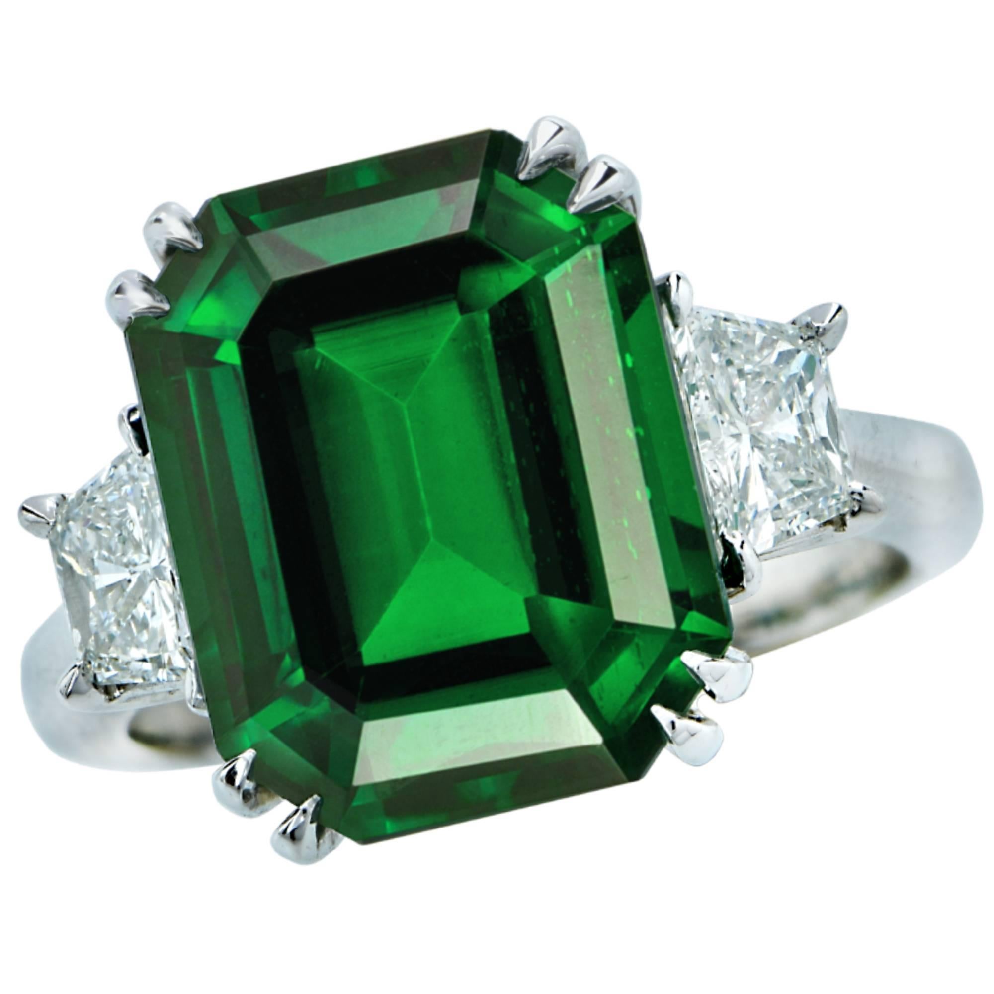 Feast your eyes on this stunning rich verdant green emerald cut Tsavorite Garnet weighing 9.79ct, complimented by 2 trapezoids weighing .77cts F color and VS clarity set in platinum. This custom made ring is a size 5.5. The face measures 13.3mm by