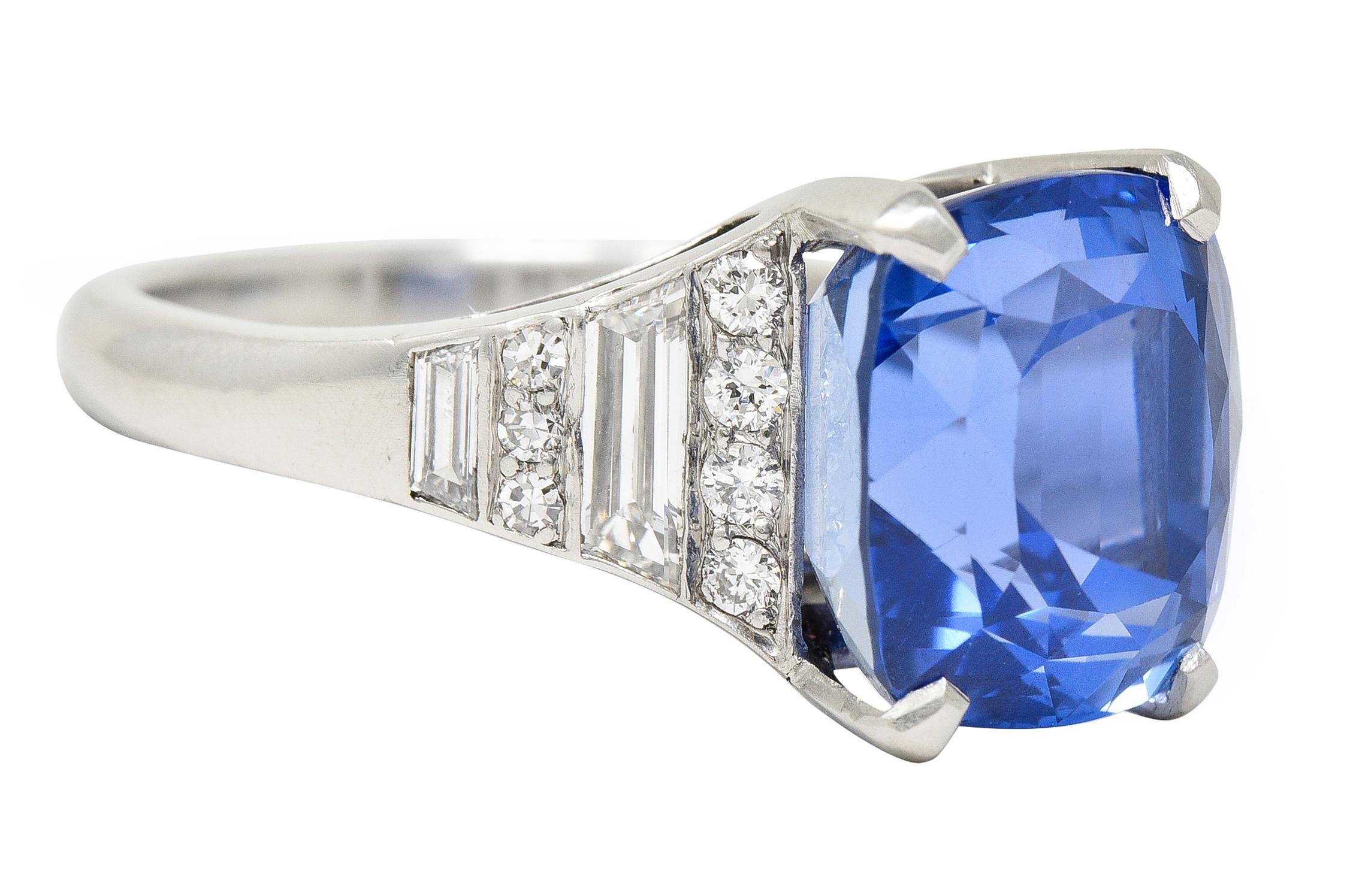 Centering a mixed cushion cut sapphire weighing 10.02 carats - transparent medium blue in color. Natural Ceylon in origin with no indications of heat treatment - prong set in basket. Flanked by cathedral shoulders set with tapered baguette and round