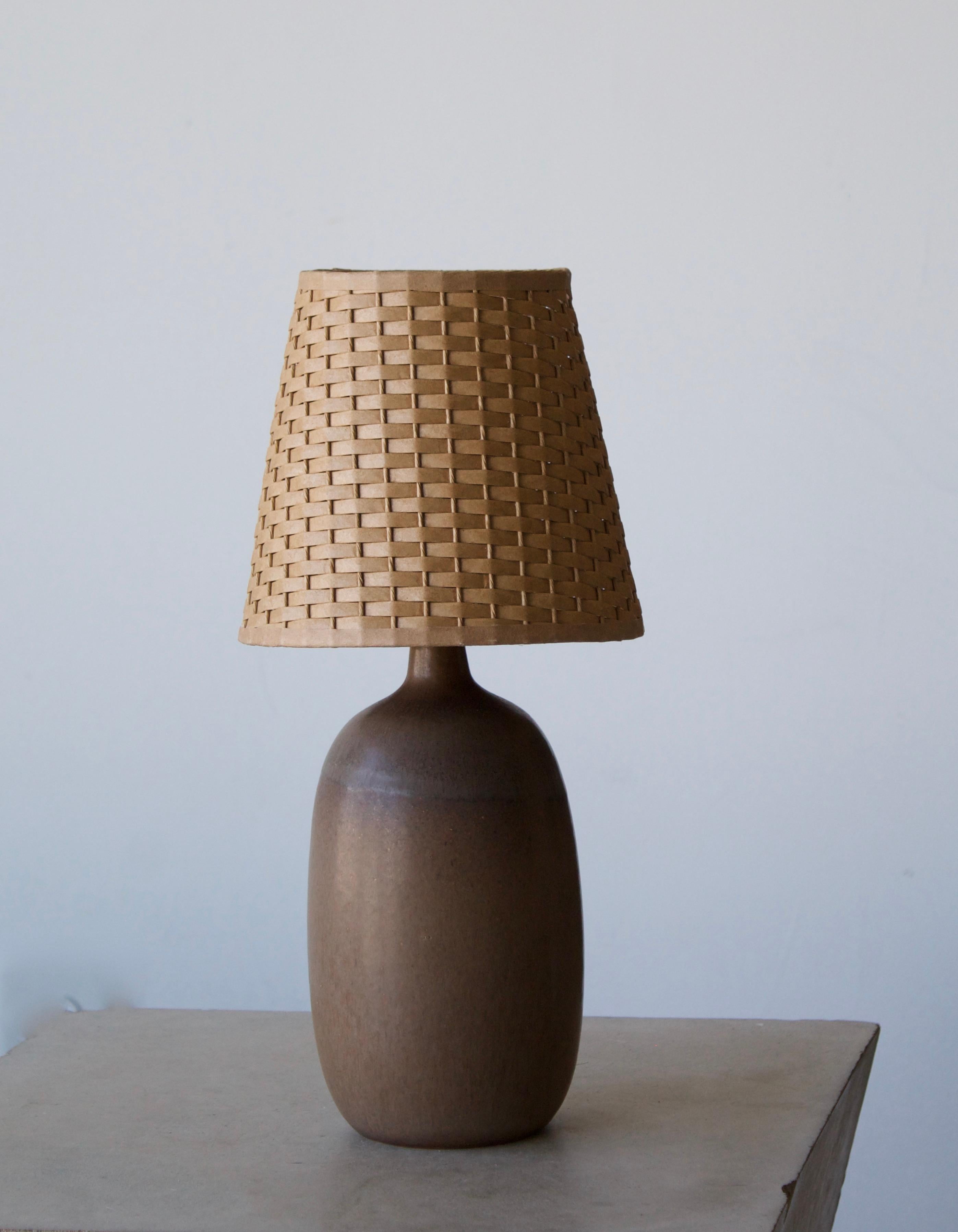 A stoneware table lamp, executed by Agne Aronsson. In his studio. Signed. Features brown glaze and very subtle decor. 

Stated dimensions exclude lampshades. Illustrated model vintage rattan lampshade can be included in purchase upon