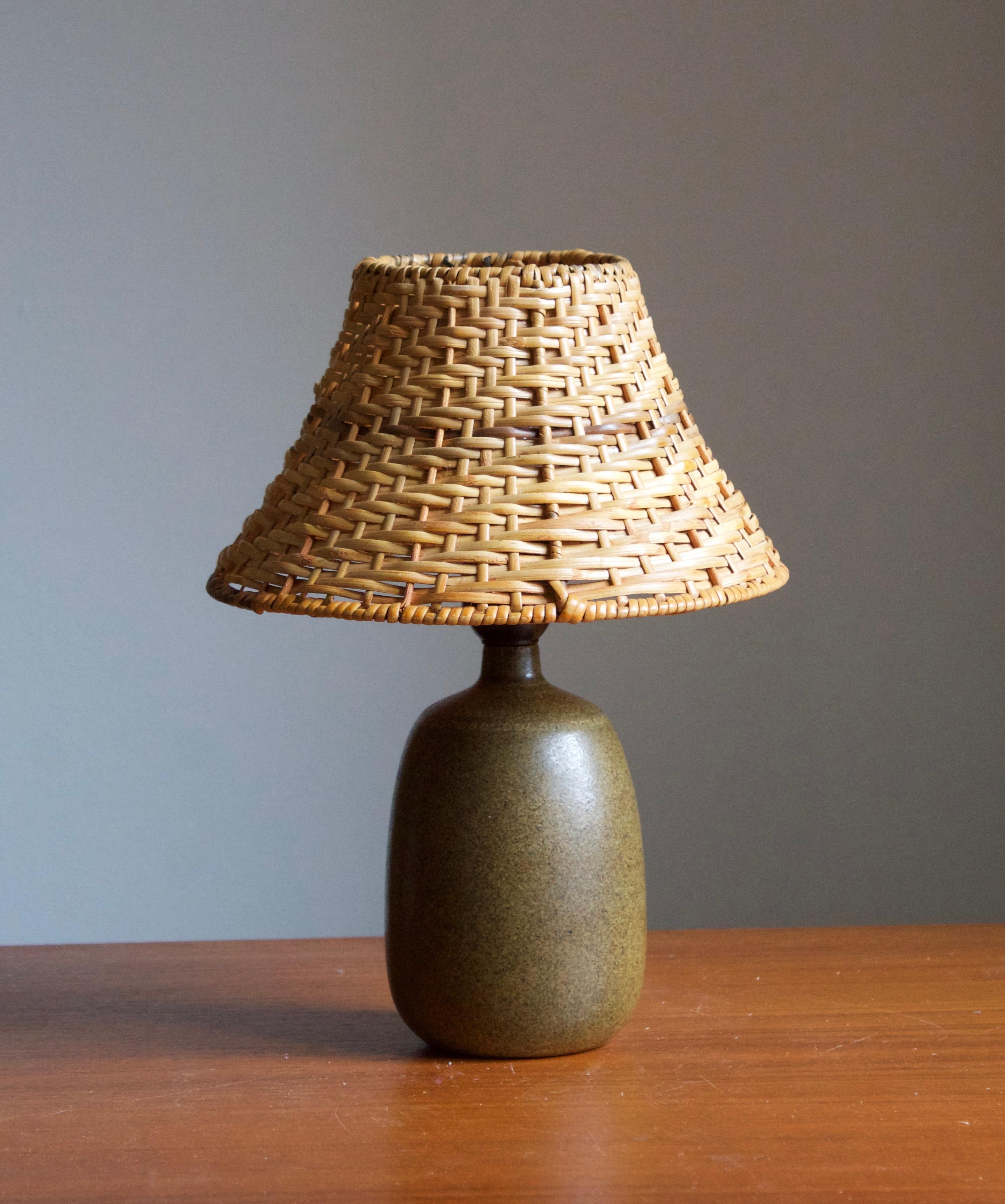 A stoneware table lamp, executed by Agne Aronsson. In his studio. Signed. Features green glaze and very subtle decor. 

Stated dimensions exclude lampshades. Illustrated model vintage rattan lampshade can be included in purchase upon