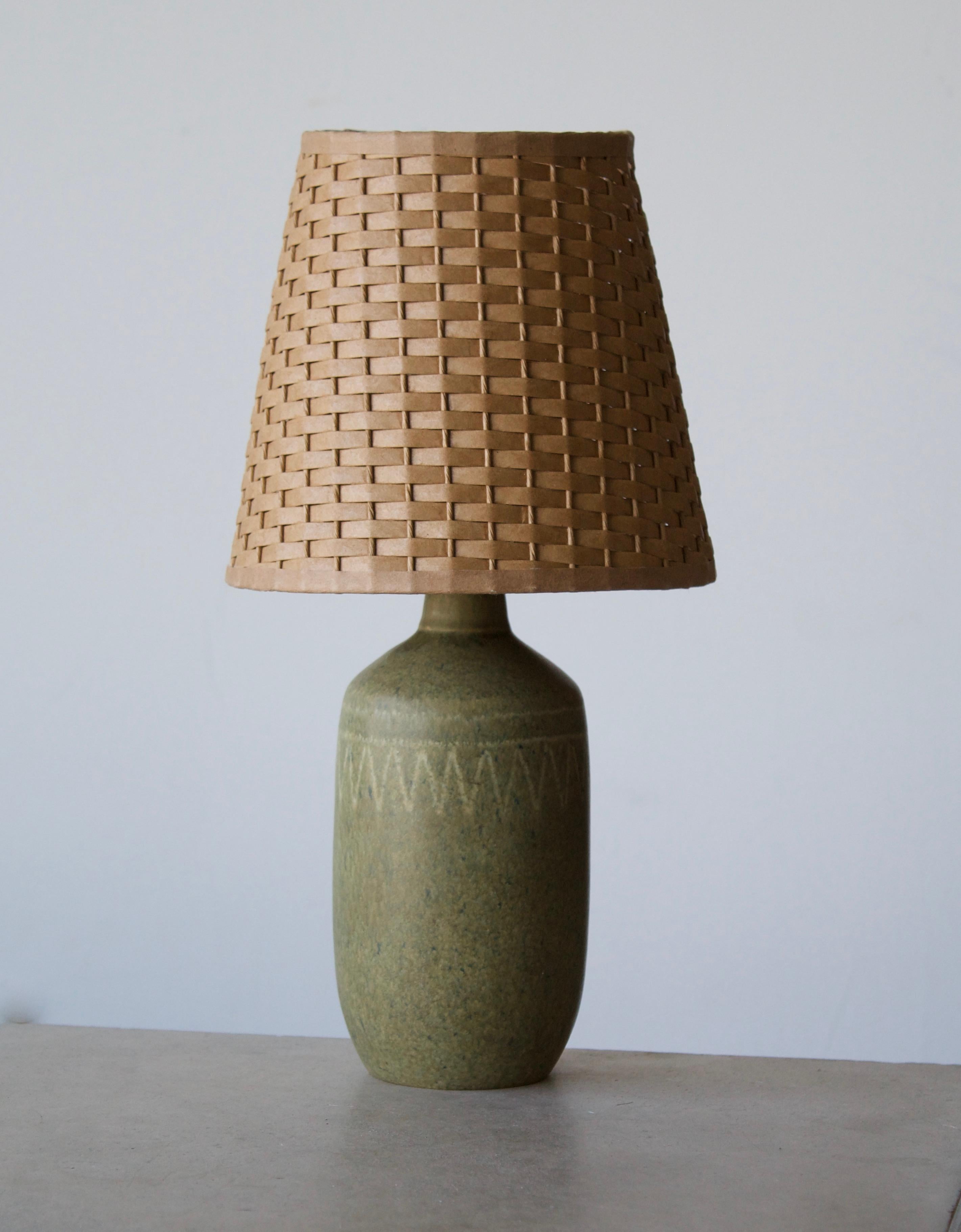 A stoneware table lamp, executed by Agne Aronsson. In his studio. Signed. Features green glaze and very subtle decor. 

Stated dimensions exclude lampshades. Illustrated model vintage rattan lampshade can be included in purchase upon