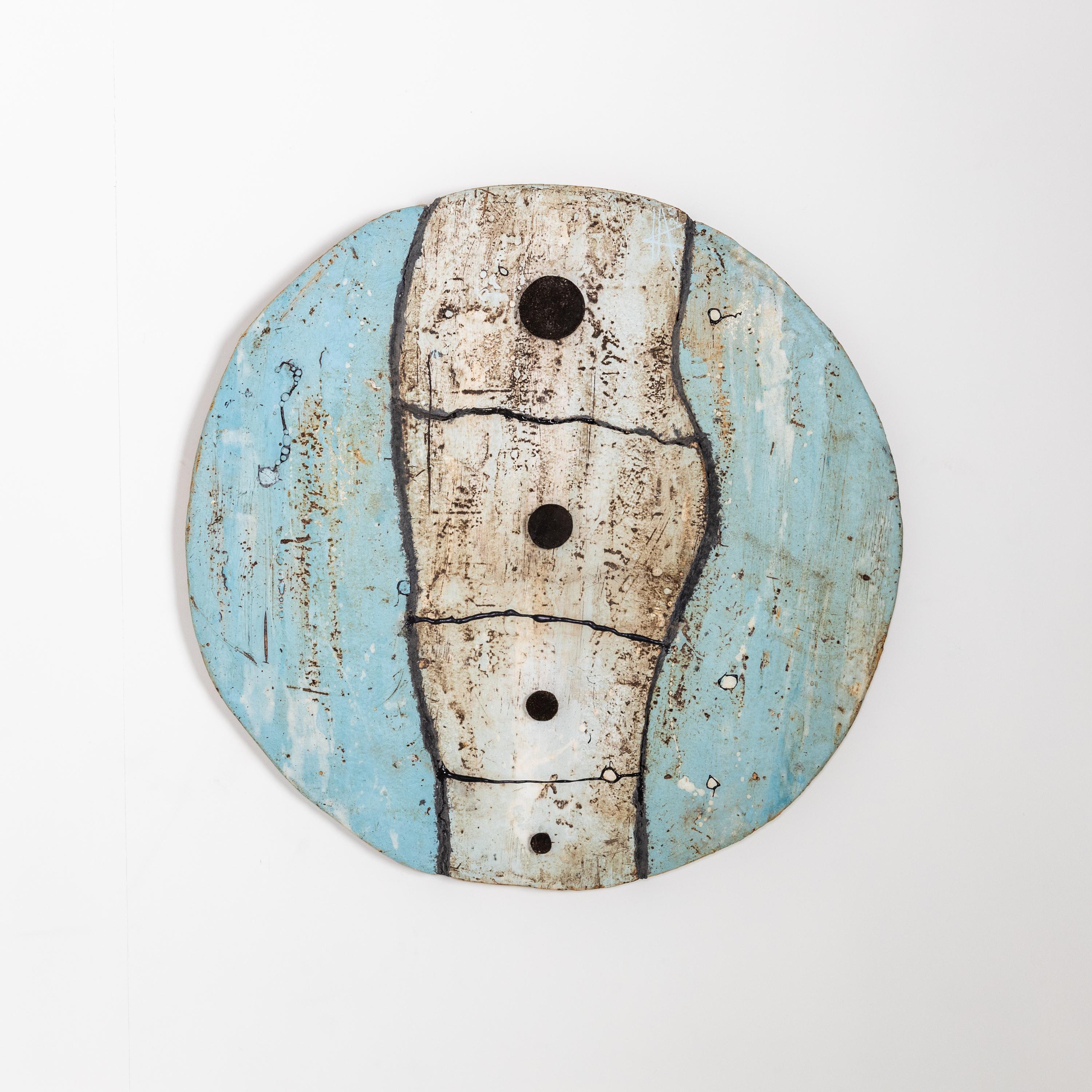 Large wall object by Agnès Debizet with four black dots on a blue and white ceramic disc.